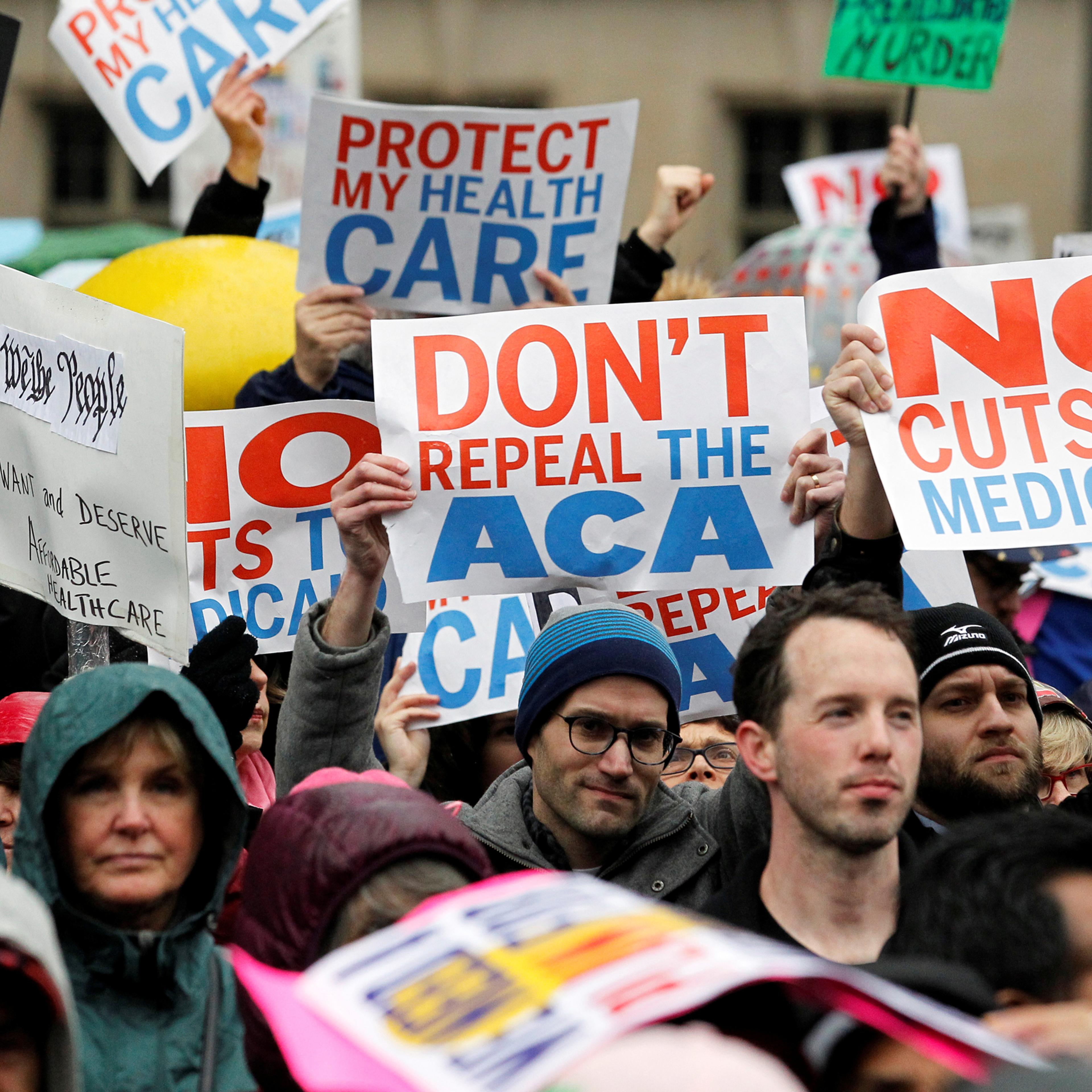 Demonstrators hold signs in support of the Affordable Care Act at a gathering before the start of a protest march near the hotel where House and Senate Republicans are attending a retreat, in Philadelphia, Pennsylvania, U.S. January 25, 2017. REUTERS/Tom
