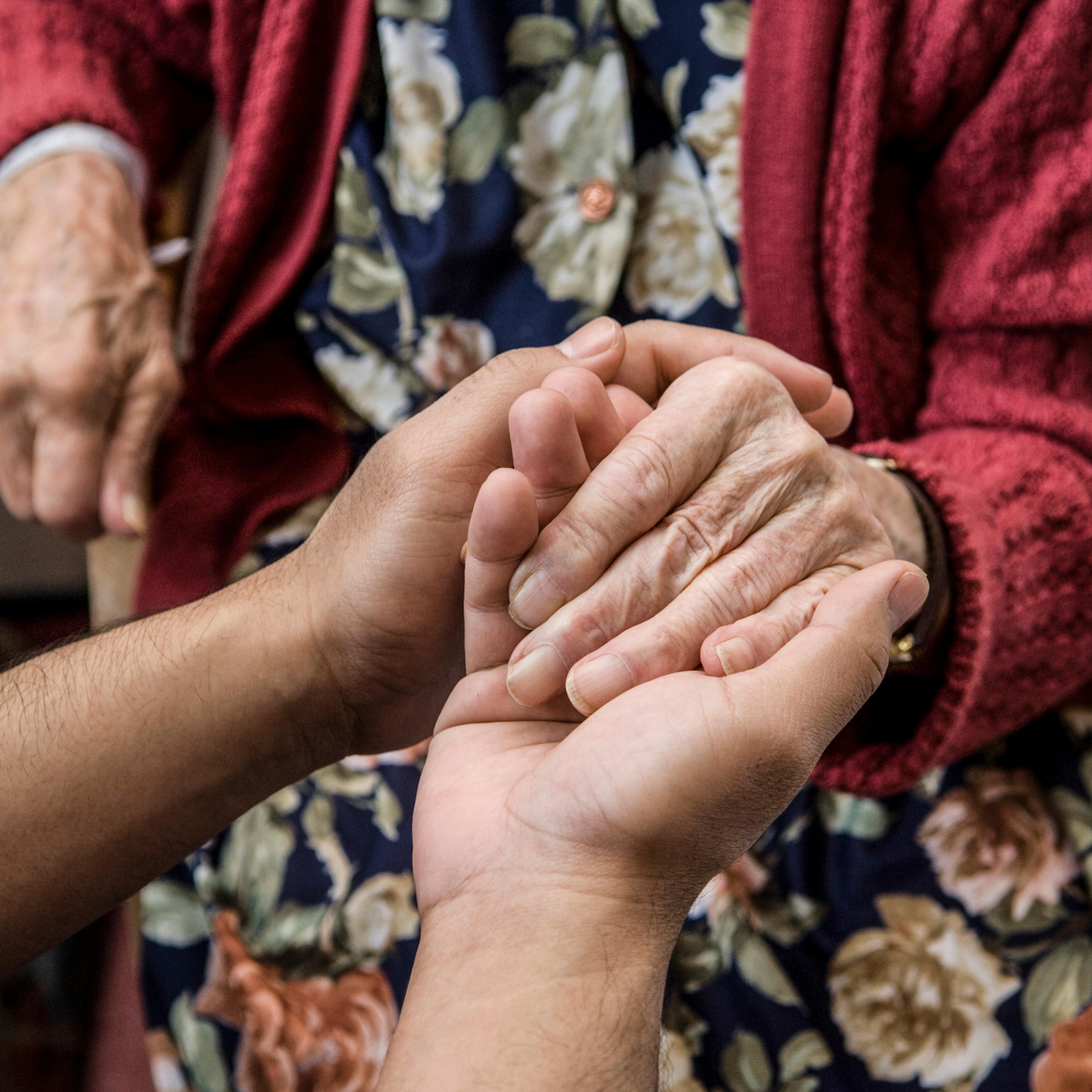 Nurse holding hands with elderly patient.