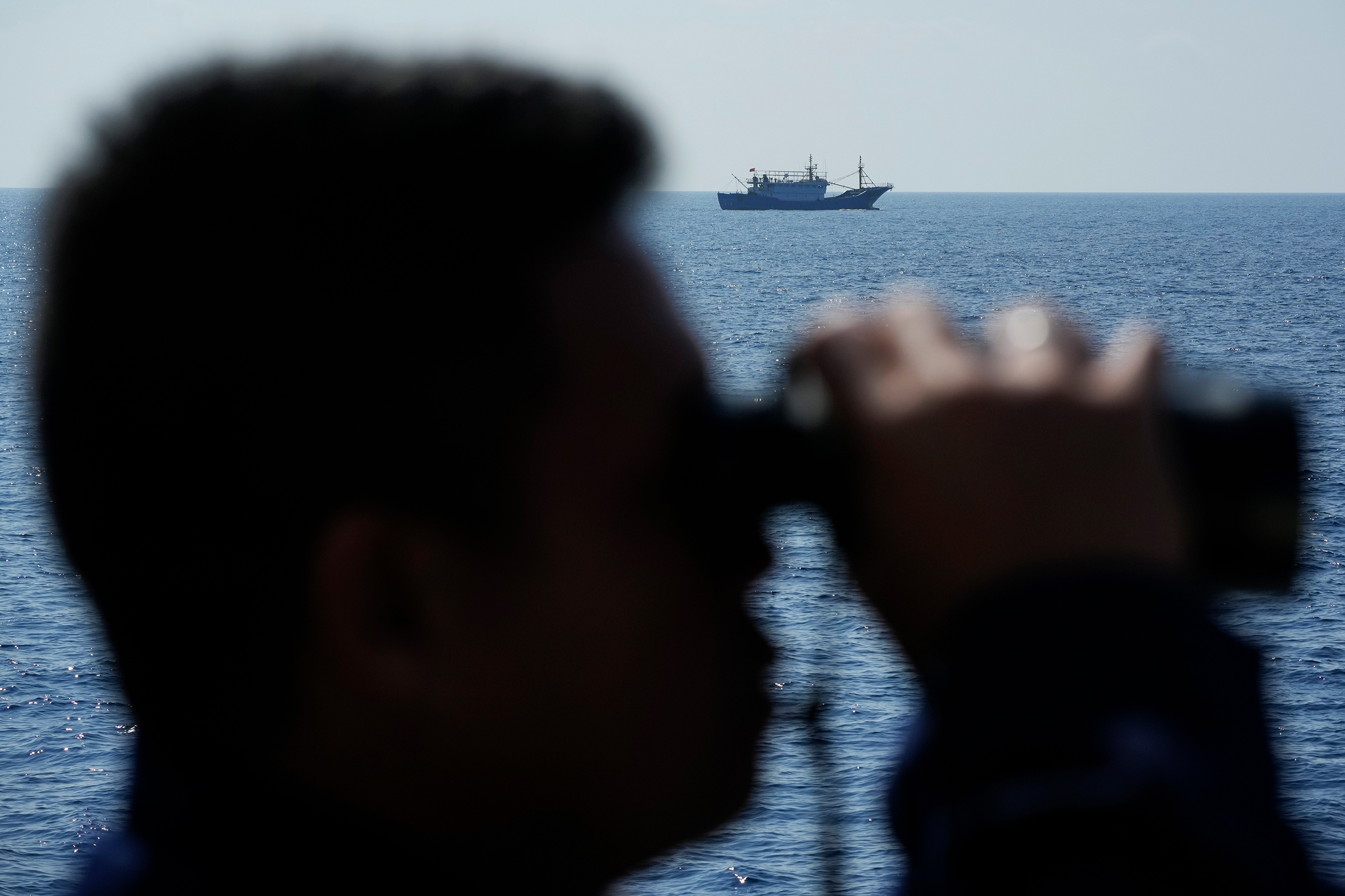 A suspected Chinese militia ship passes as members onboard the Philippine Coast Guard BRP Malabrigo drives them away from Philippine-occupied areas in the South China Sea on April 21.