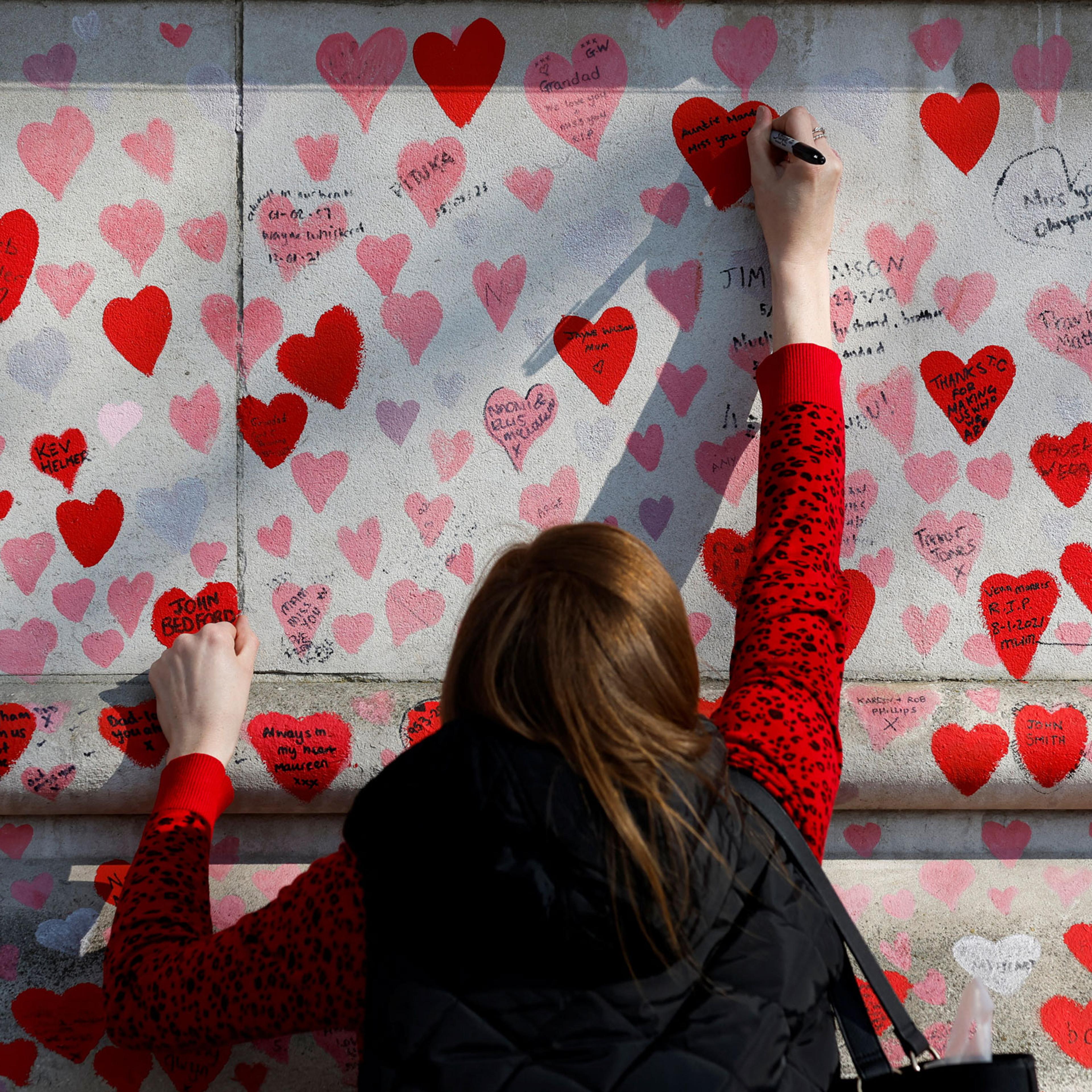 A person writes a message on The National Covid Memorial Wall, on national day of reflection to mark the two year anniversary of the United Kingdom going into national lockdown, in London, on March 23, 2022.