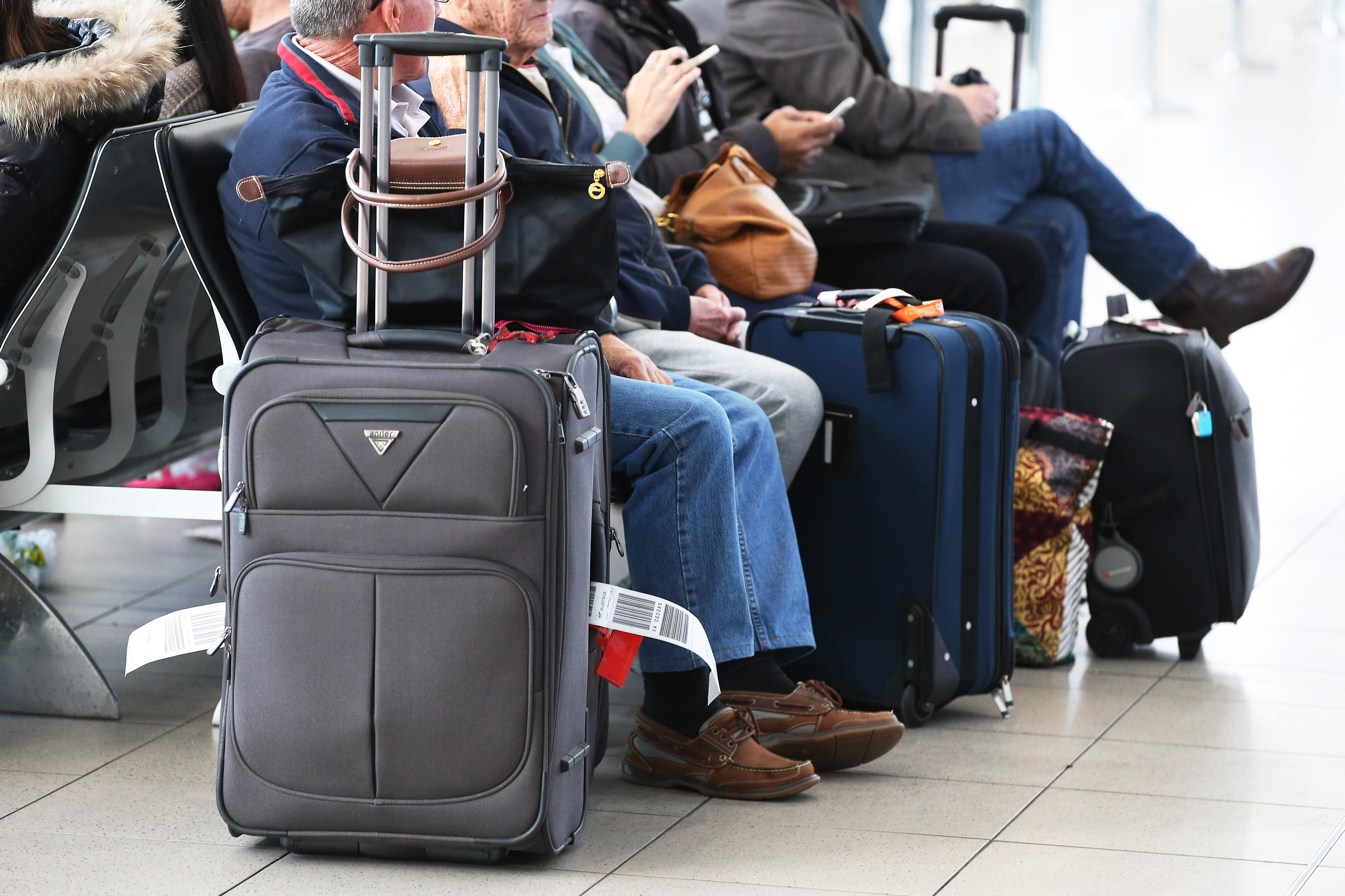 Passengers sit with their luggage while waiting to board a flight in the domestic terminal at Sydney Airport in Sydney, Aug. 27, 2014.