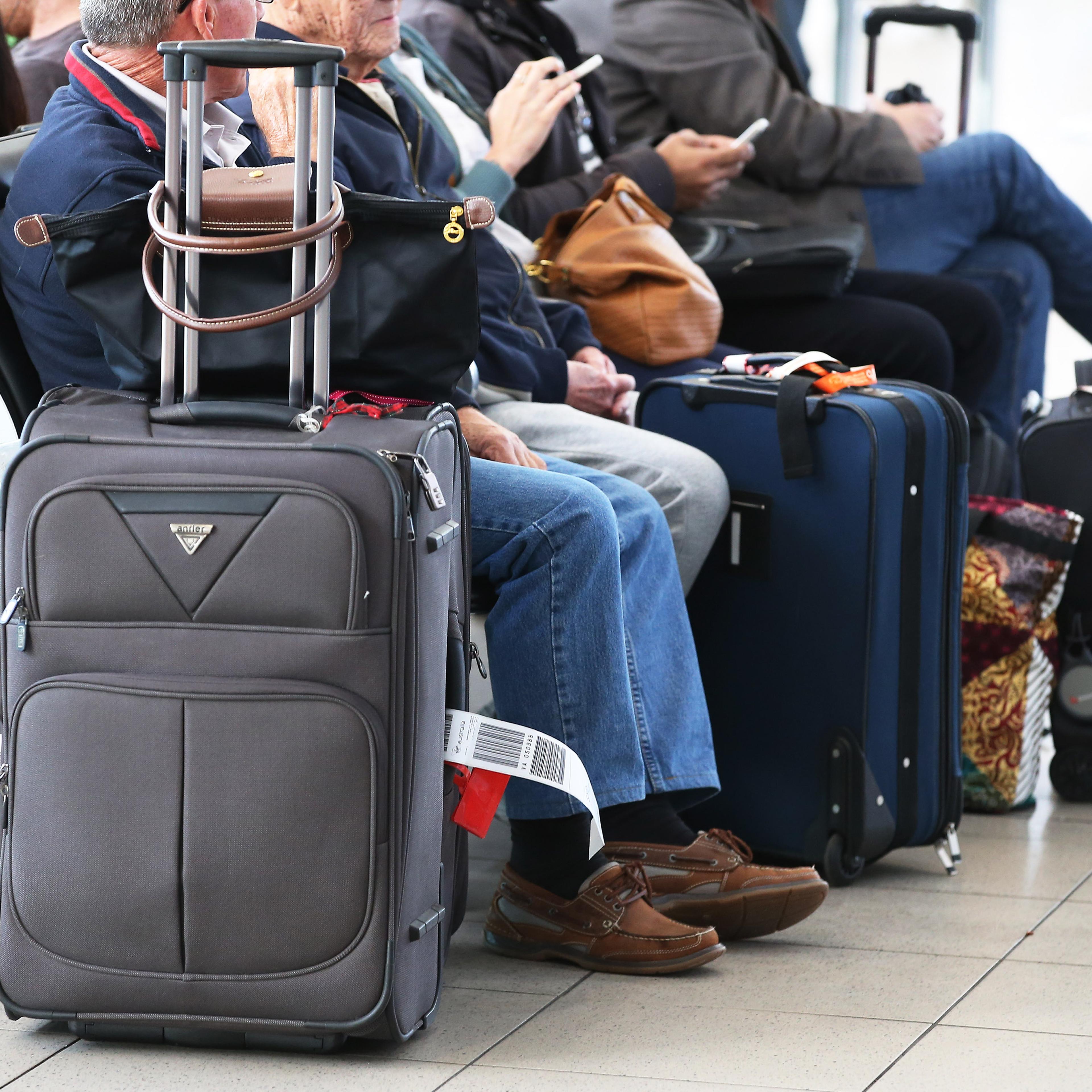 Passengers sit with their luggage while waiting to board a flight in the domestic terminal at Sydney Airport in Sydney, Aug. 27, 2014.