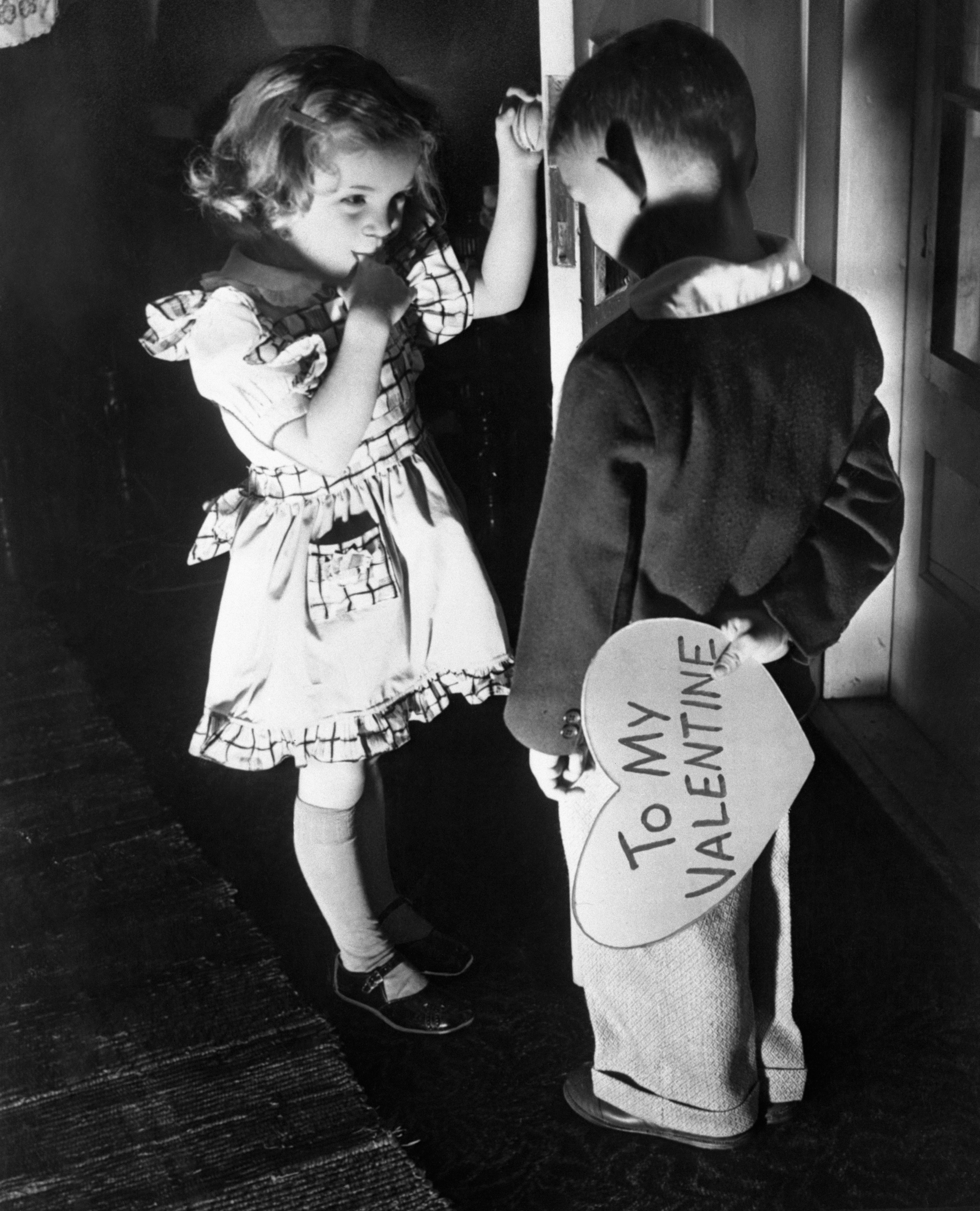 Girl and boy (6-7), boy holding Valentine card