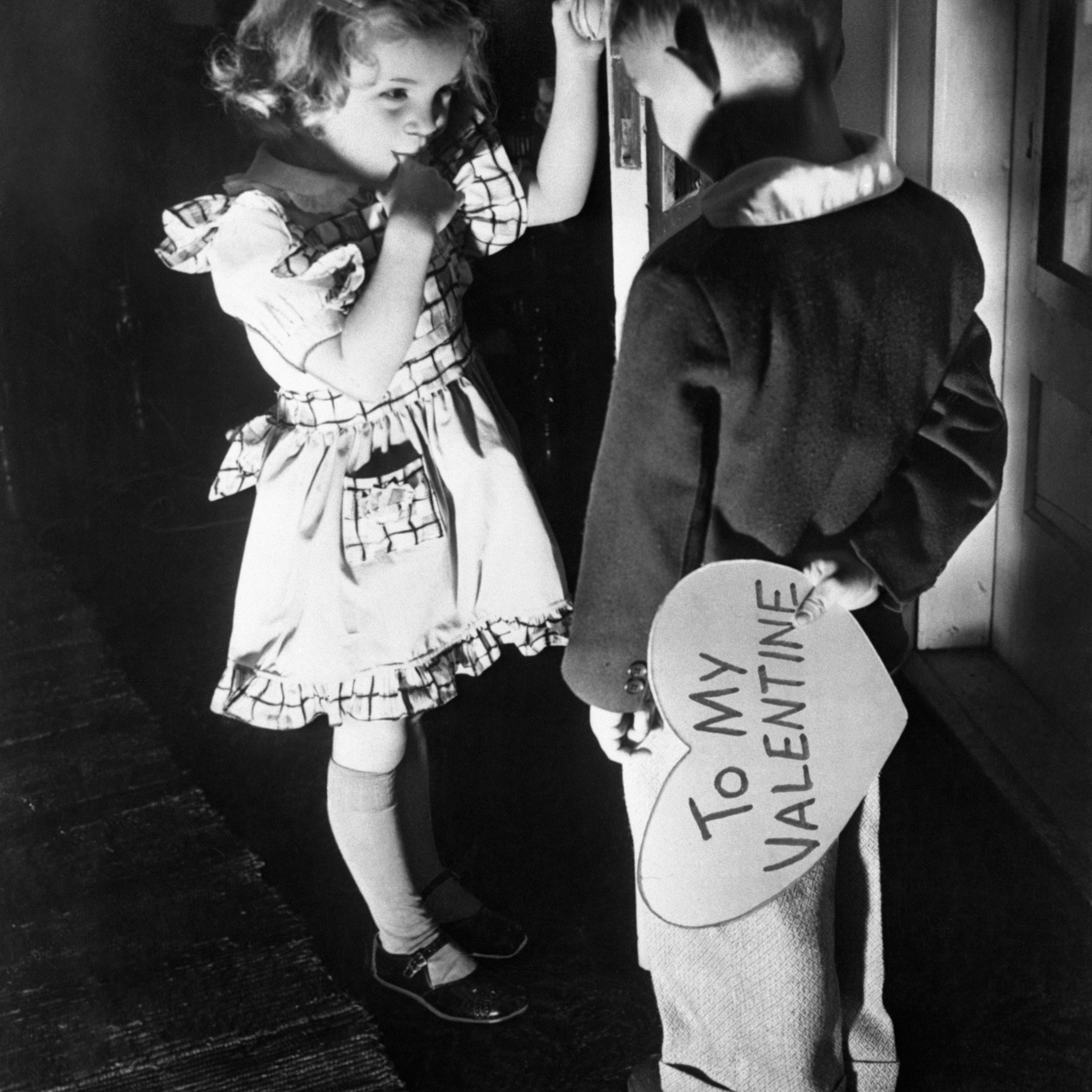 Girl and boy (6-7), boy holding Valentine card