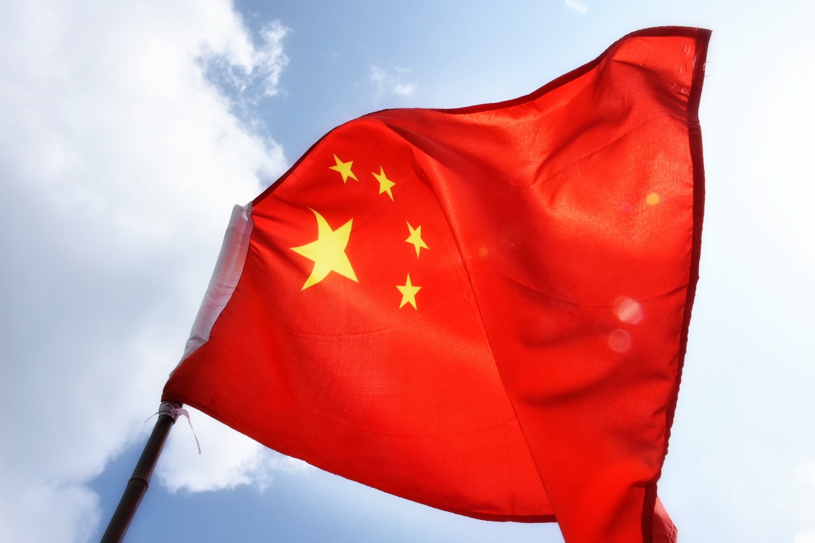 Low Angle View Of Chinese Flag Waving Against Sky