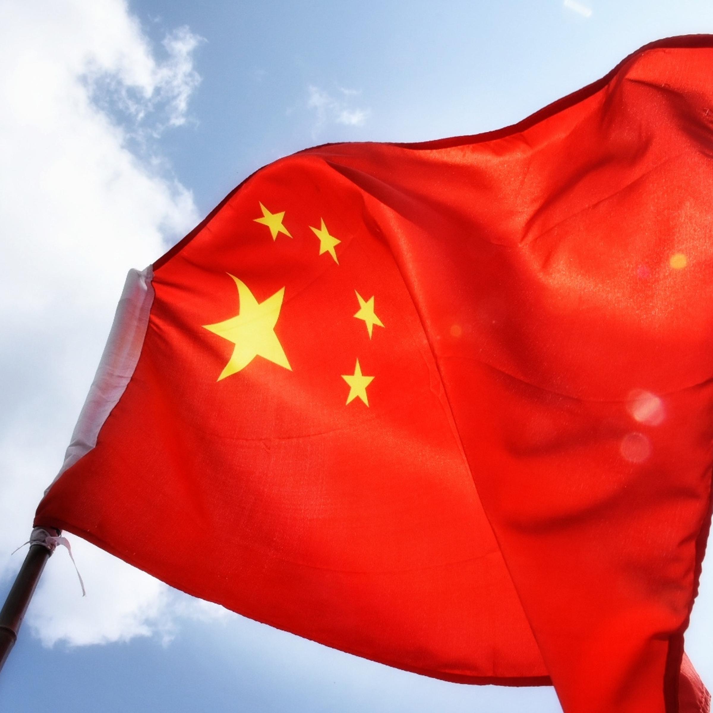 Low Angle View Of Chinese Flag Waving Against Sky