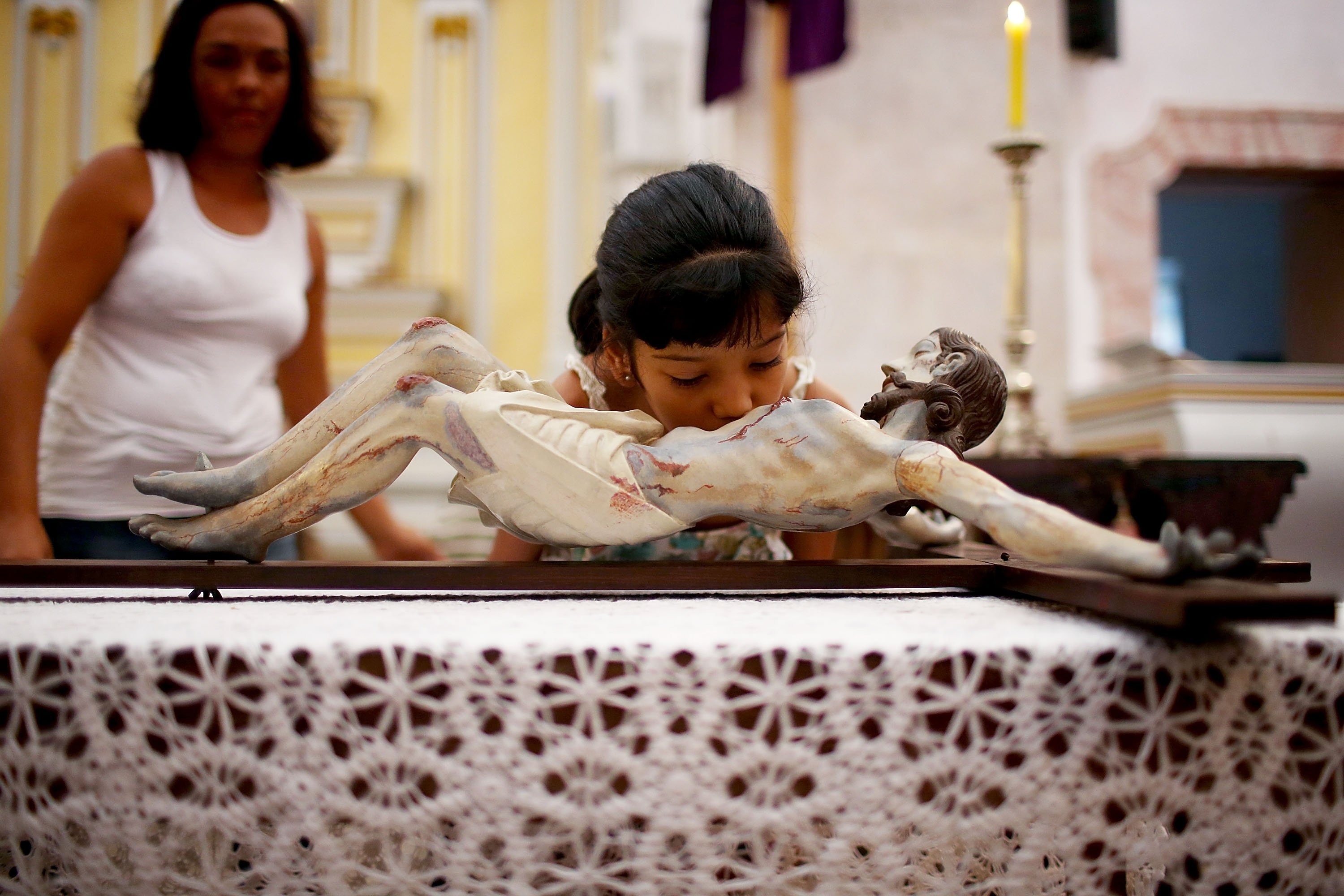 A young worshiper kisses a statue of Christ hanging on the cross during Holy Week festivities on April 18, 2014 in Paraty, Brazil.