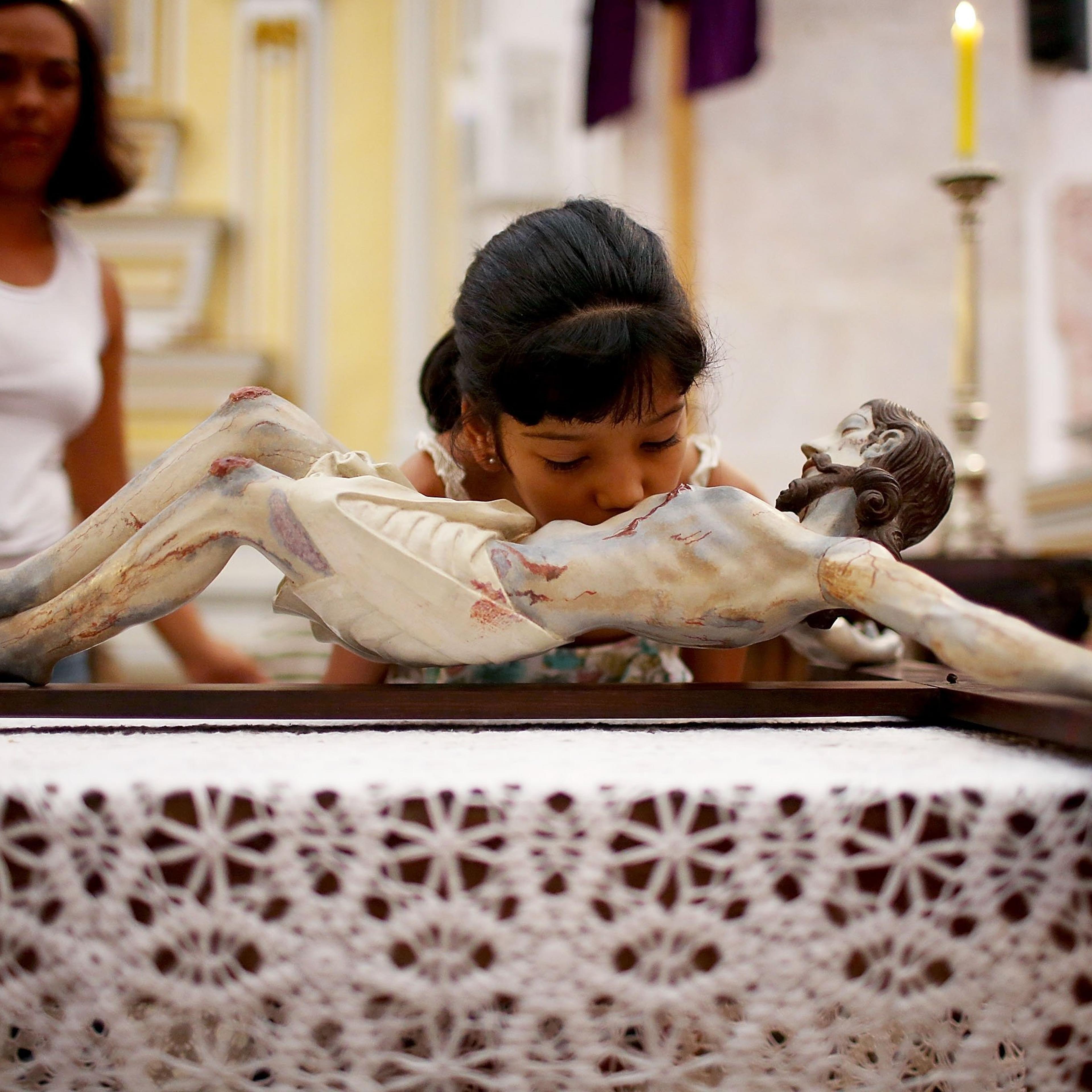 A young worshiper kisses a statue of Christ hanging on the cross during Holy Week festivities on April 18, 2014 in Paraty, Brazil.
