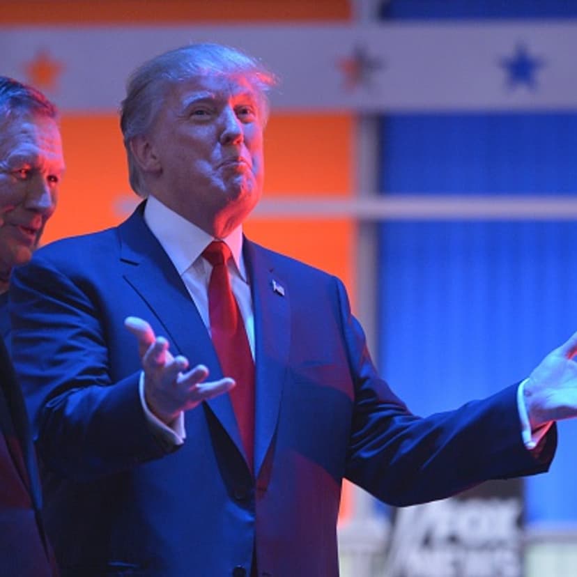 Real estate tycoon Donald Trump (R) confers with Ohio Governor John Kasich (L) during a break in the Republican presidential primary debate on August 6, 2015 at the Quicken Loans Arena in Cleveland, Ohio.