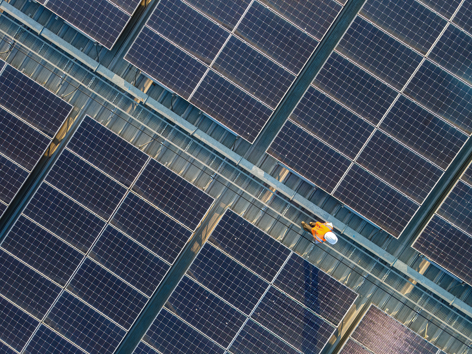 Aerial view of engineers working at solar panels roof.