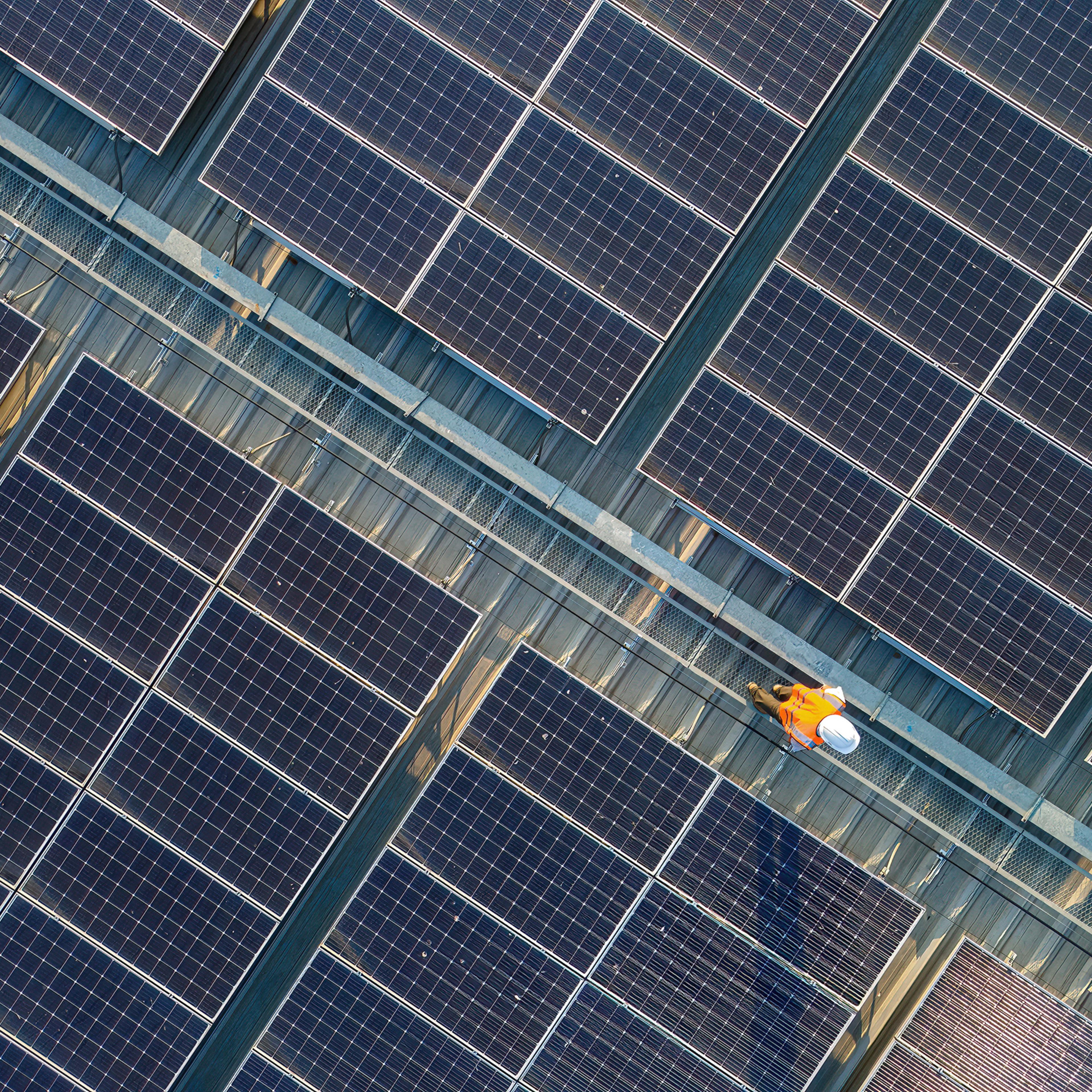 Aerial view of engineers working at solar panels roof.
