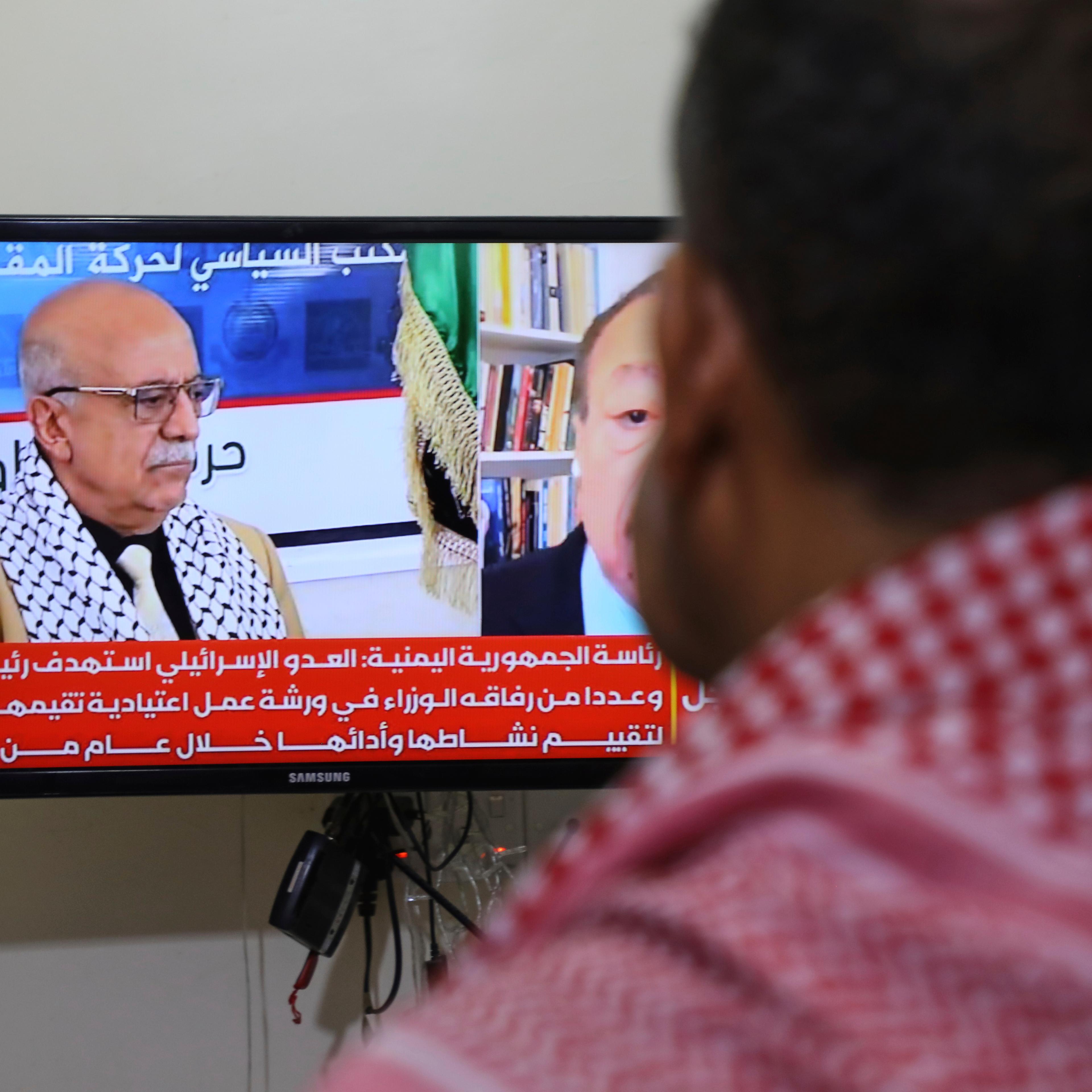 A man watches the news on TV, displaying footage of Ahmed al-Rahawi, the prime minister of the Houthi-controlled government, who was killed, along with others, in Thursday's Israeli strikes on the capital, in Sanaa, Yemen, Saturday, Aug. 30, 2025