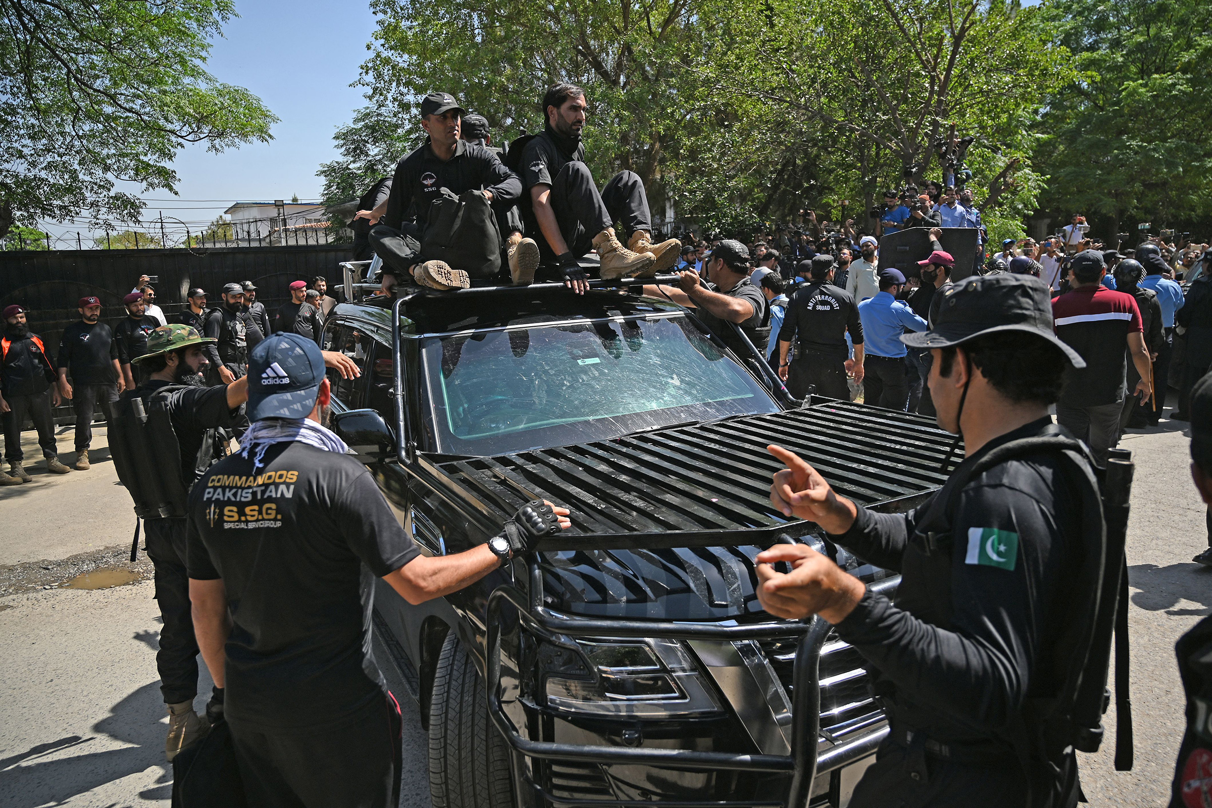 Security personnel escort a car carrying Pakistan's former Prime Minister Imran Khan as he arrives at the high court in Islamabad on May 9. Imran Khan was arrested today during a court appearance for one of dozens of cases pending since he was booted from office last year. 