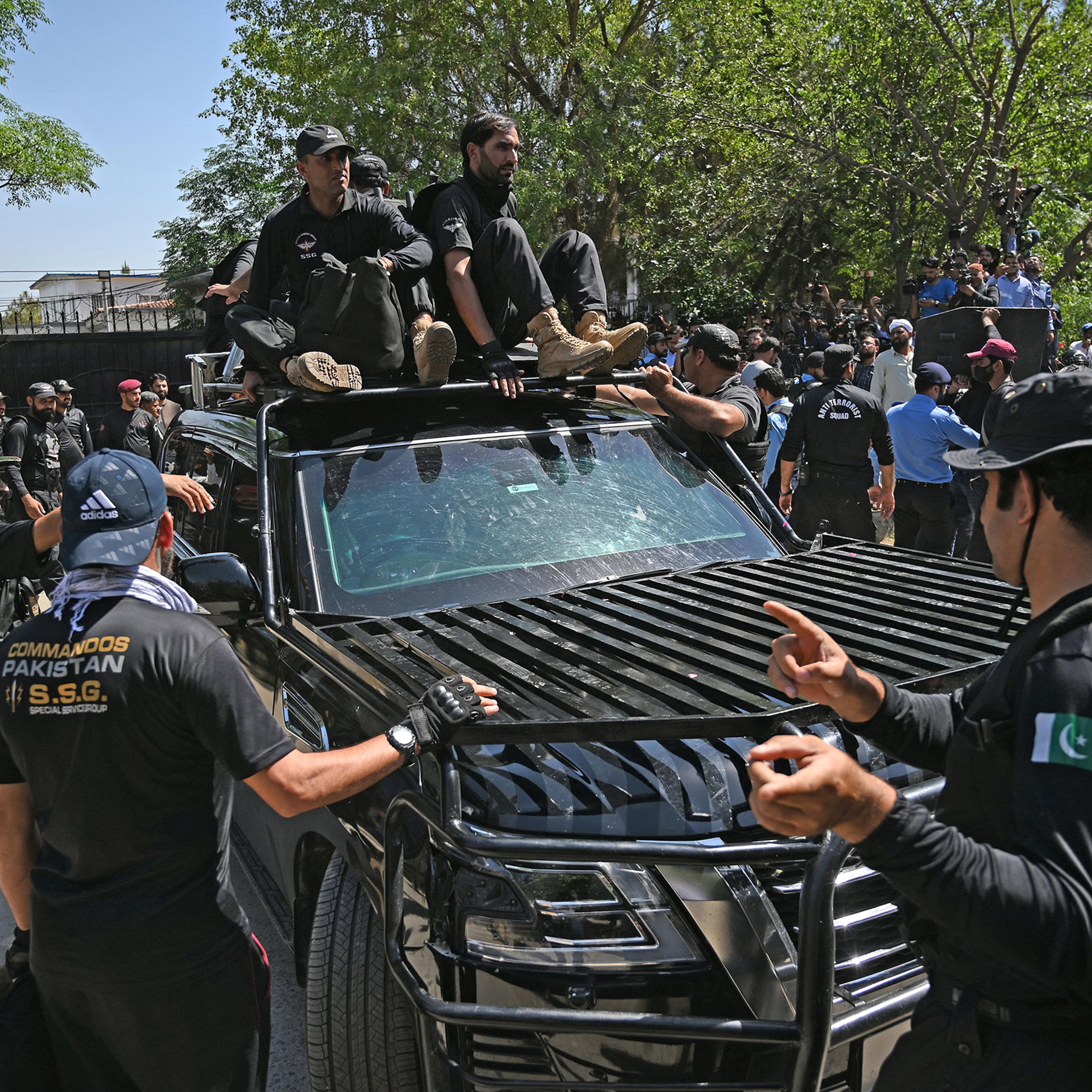 Security personnel escort a car carrying Pakistan's former Prime Minister Imran Khan as he arrives at the high court in Islamabad on May 9. Imran Khan was arrested today during a court appearance for one of dozens of cases pending since he was booted from office last year.