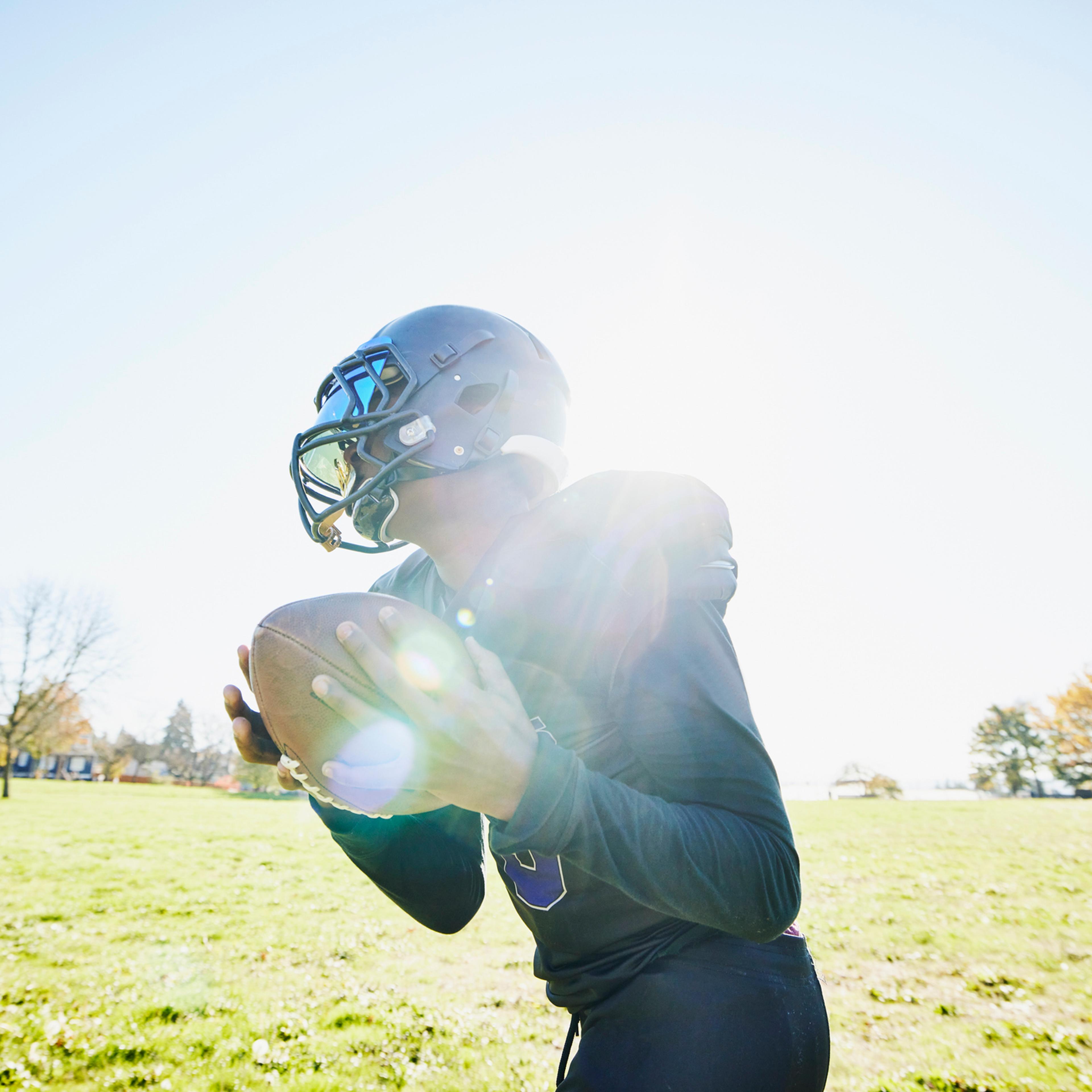 Medium shot of young football player catching pass during practice on fall afternoon