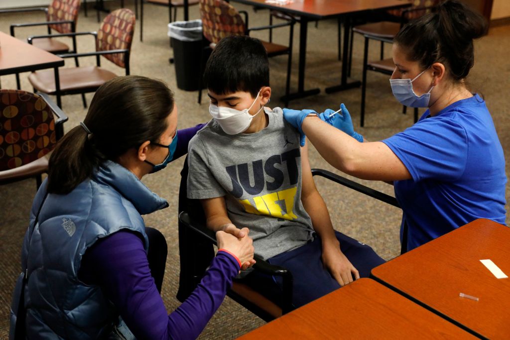 Jamie Blank (L) holds her son, Ari Blank's hand as he receives the Pfizer-BioNTech COVID-19 vaccine