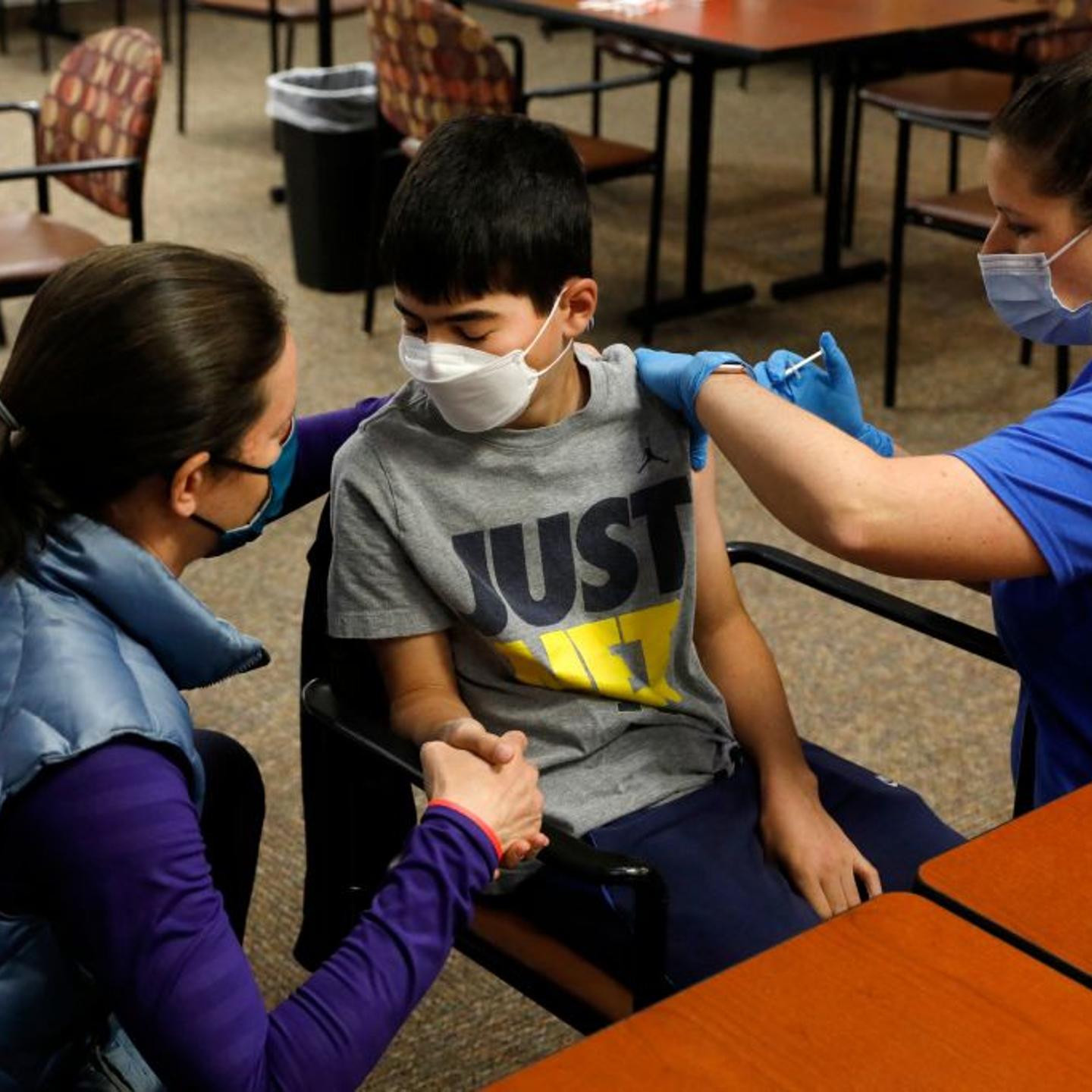 Jamie Blank (L) holds her son, Ari Blank's hand as he receives the Pfizer-BioNTech COVID-19 vaccine