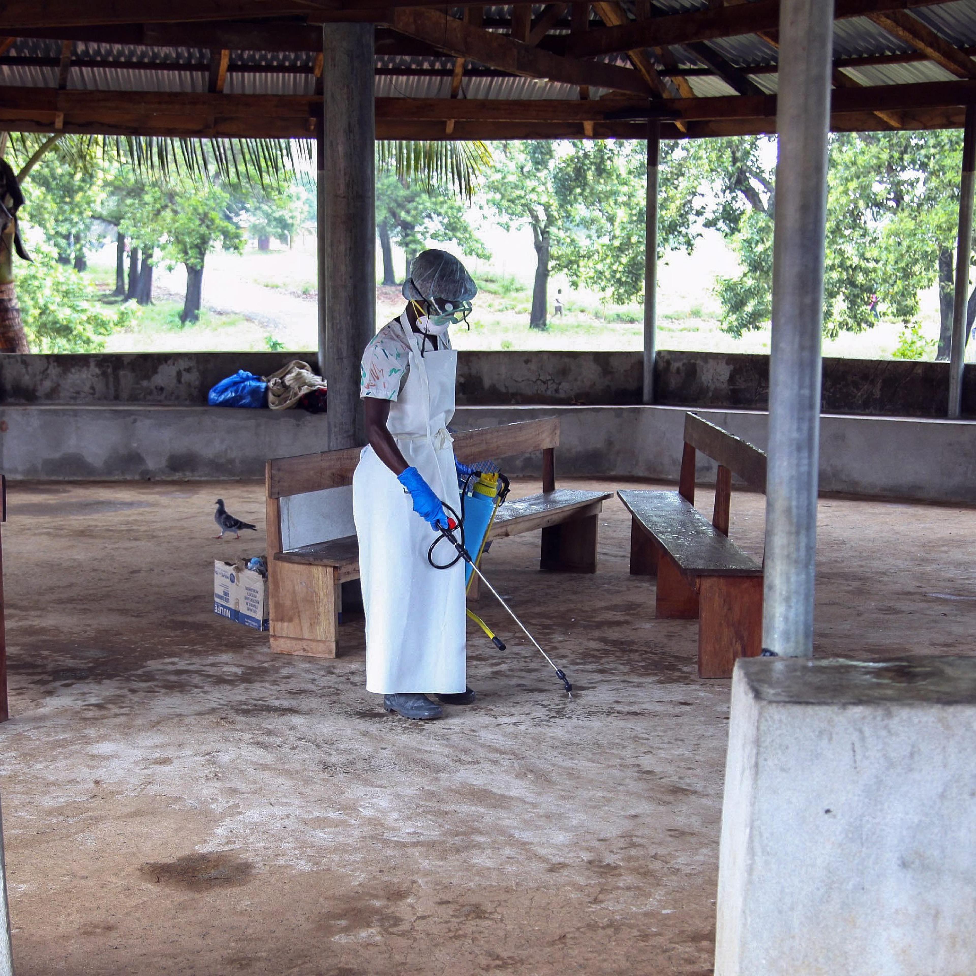 A nurse from Liberia sprays preventives to disinfect the waiting area for visitors at the ELWA Hospital where a US doctor Kent Bradley is being quarantined in the hospitals isolation unit having contracted the Ebola virus, Monrovia, Liberia, 28 July 2014