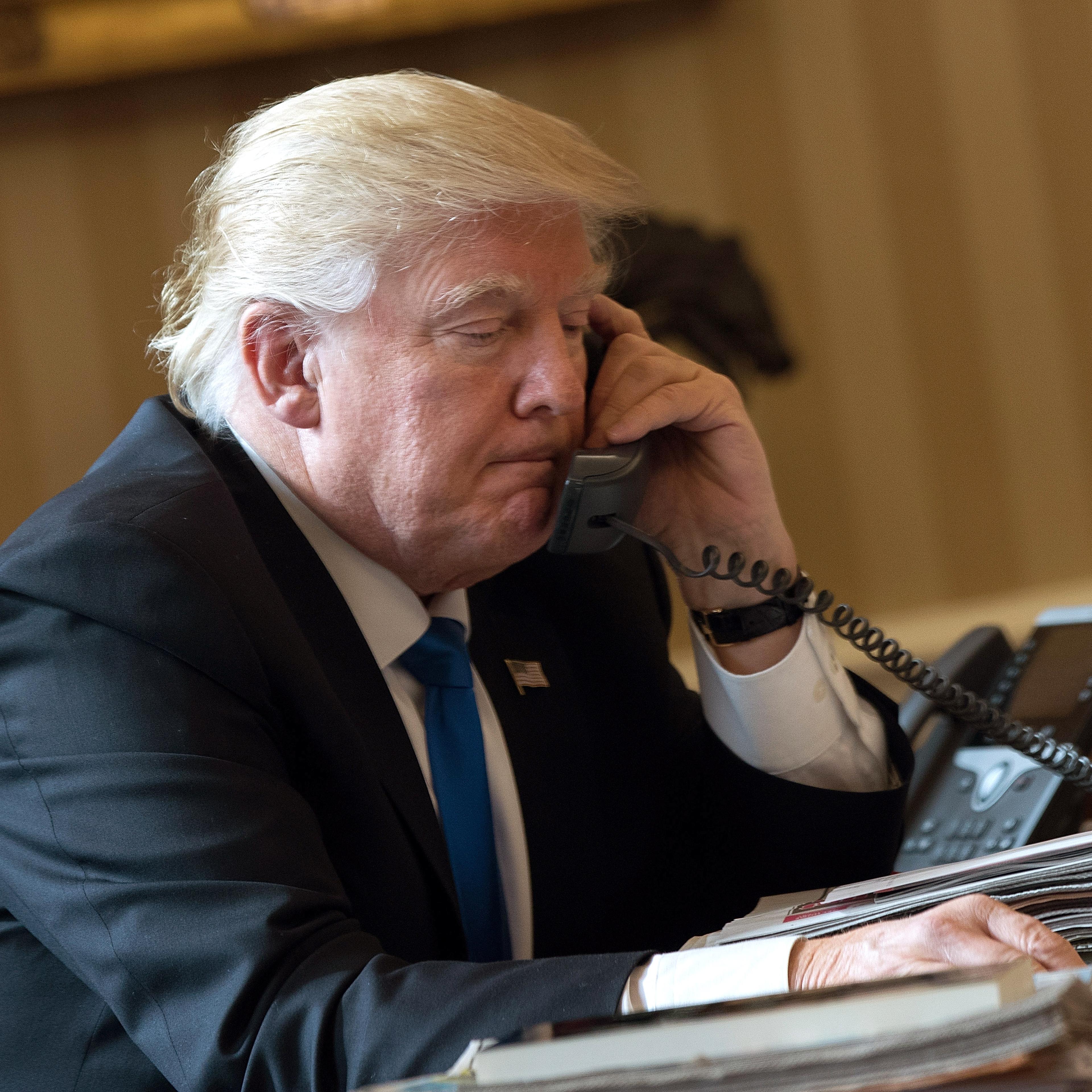 President Donald Trump speaks on the phone with Russian President Vladimir Putin in the Oval Office of the White House, January 28, 2017 in Washington, DC.