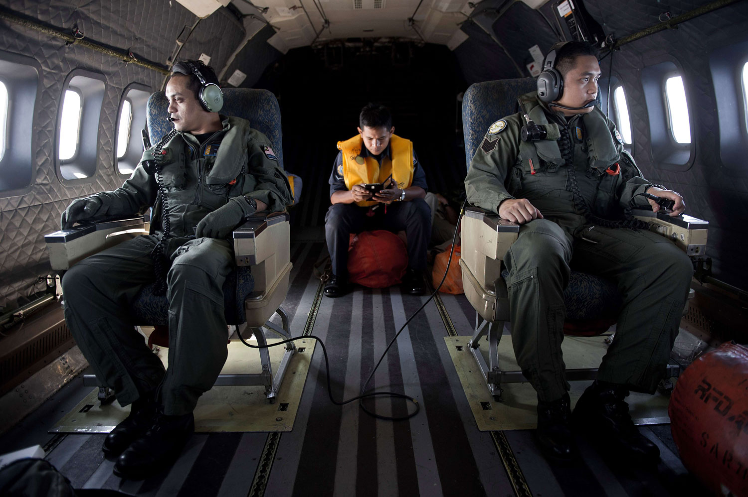 Crew members look out the windows from a Malaysian Air Force CN235 aircraft during a search and rescue (SAR) operation to find the missing Malaysia Airlines flight MH370 plane over the Strait of Malacca on March 14, 2014.