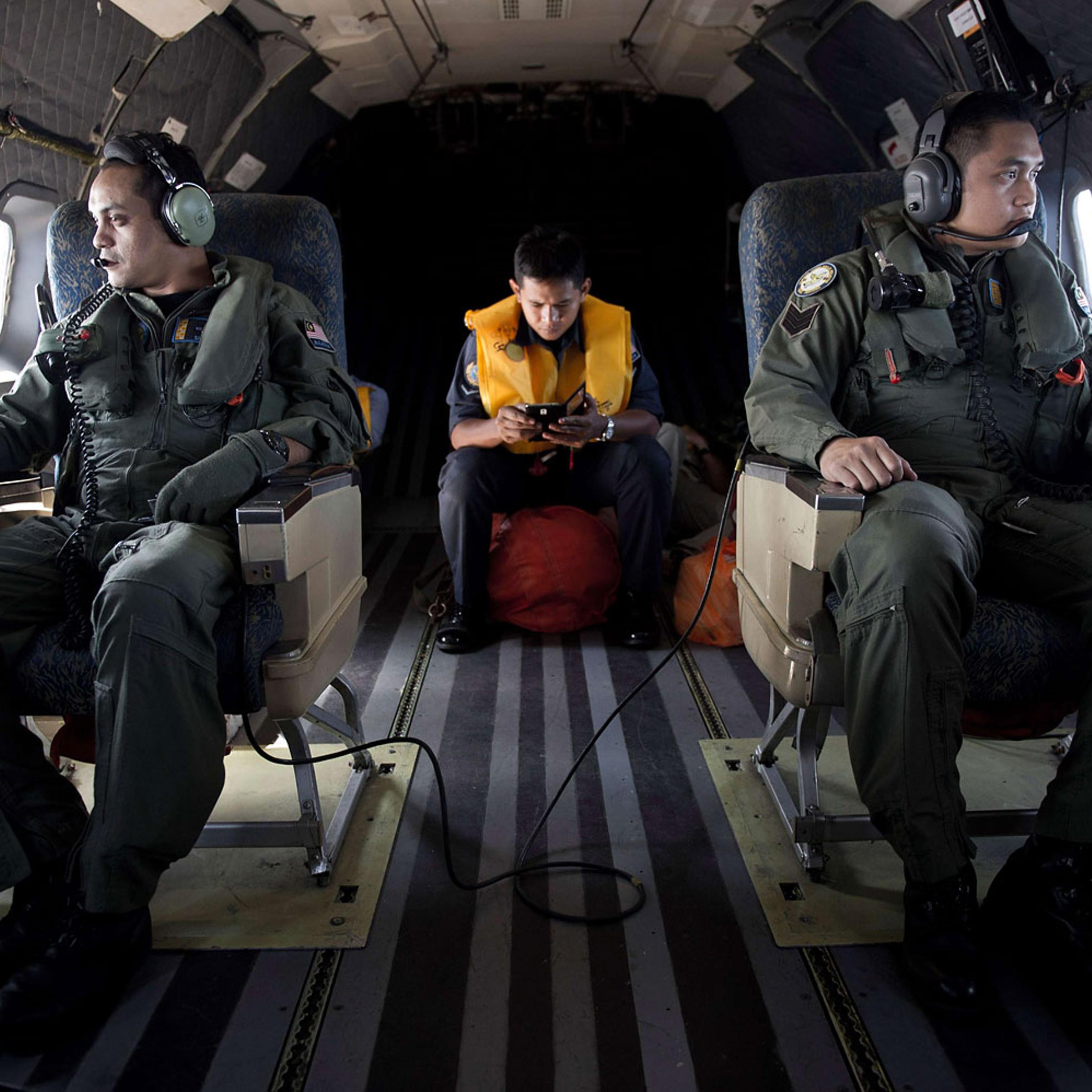 Crew members look out the windows from a Malaysian Air Force CN235 aircraft during a search and rescue (SAR) operation to find the missing Malaysia Airlines flight MH370 plane over the Strait of Malacca on March 14, 2014.