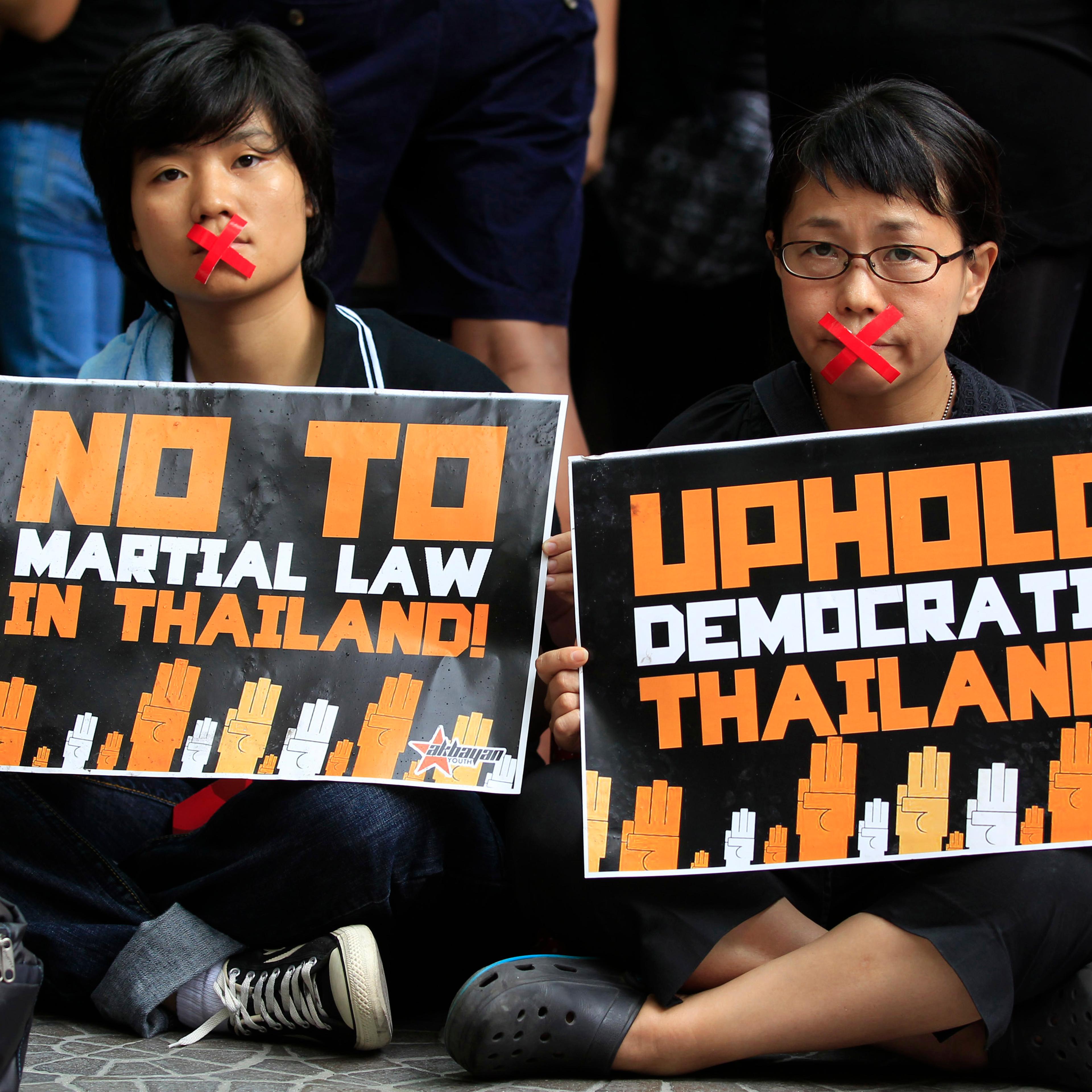 Activists, with their mouths taped up as a form of protest against the ongoing military rule in Thailand, hold placards during a picket in front of the Thai embassy in Manila