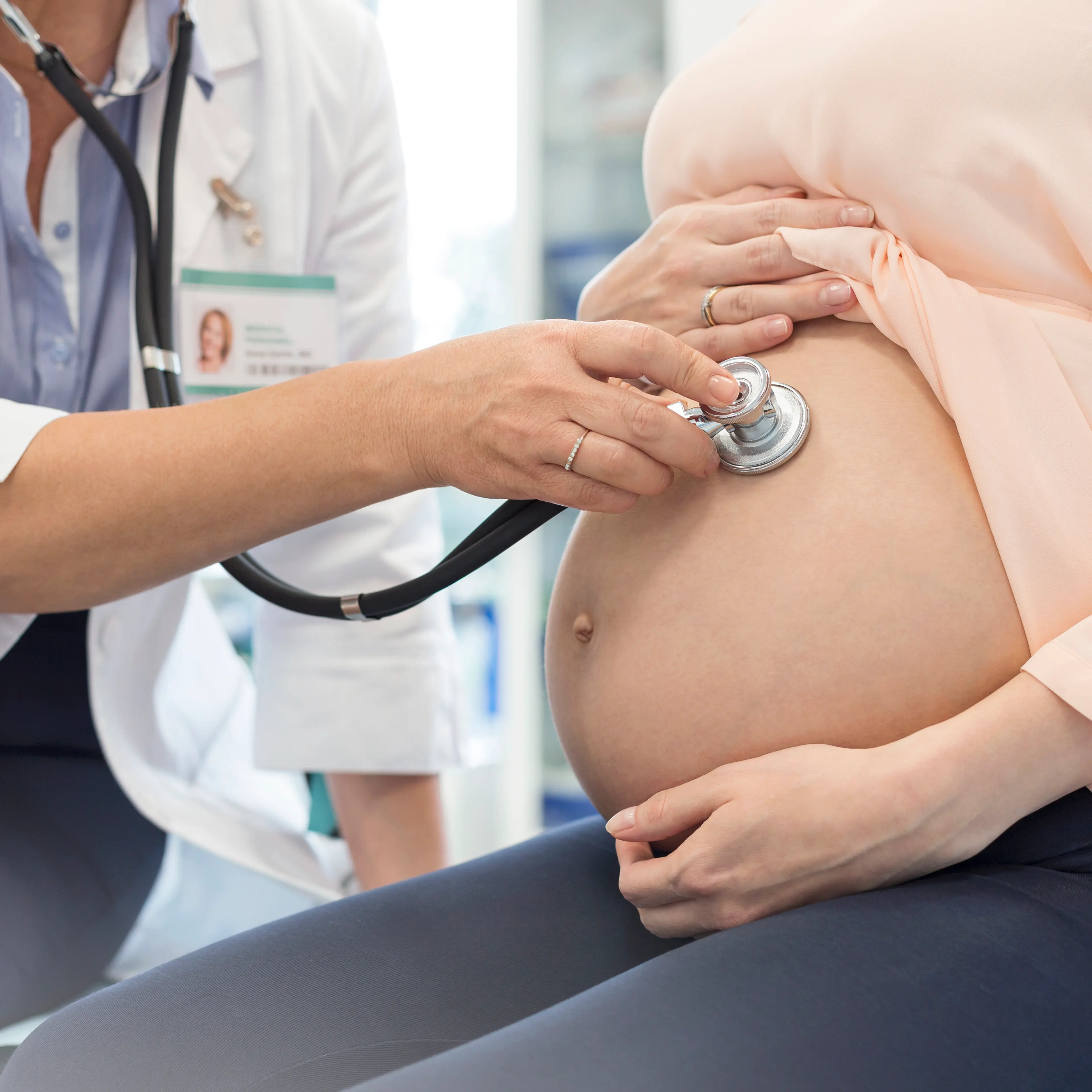 Doctor using stethoscope on pregnant patients stomach