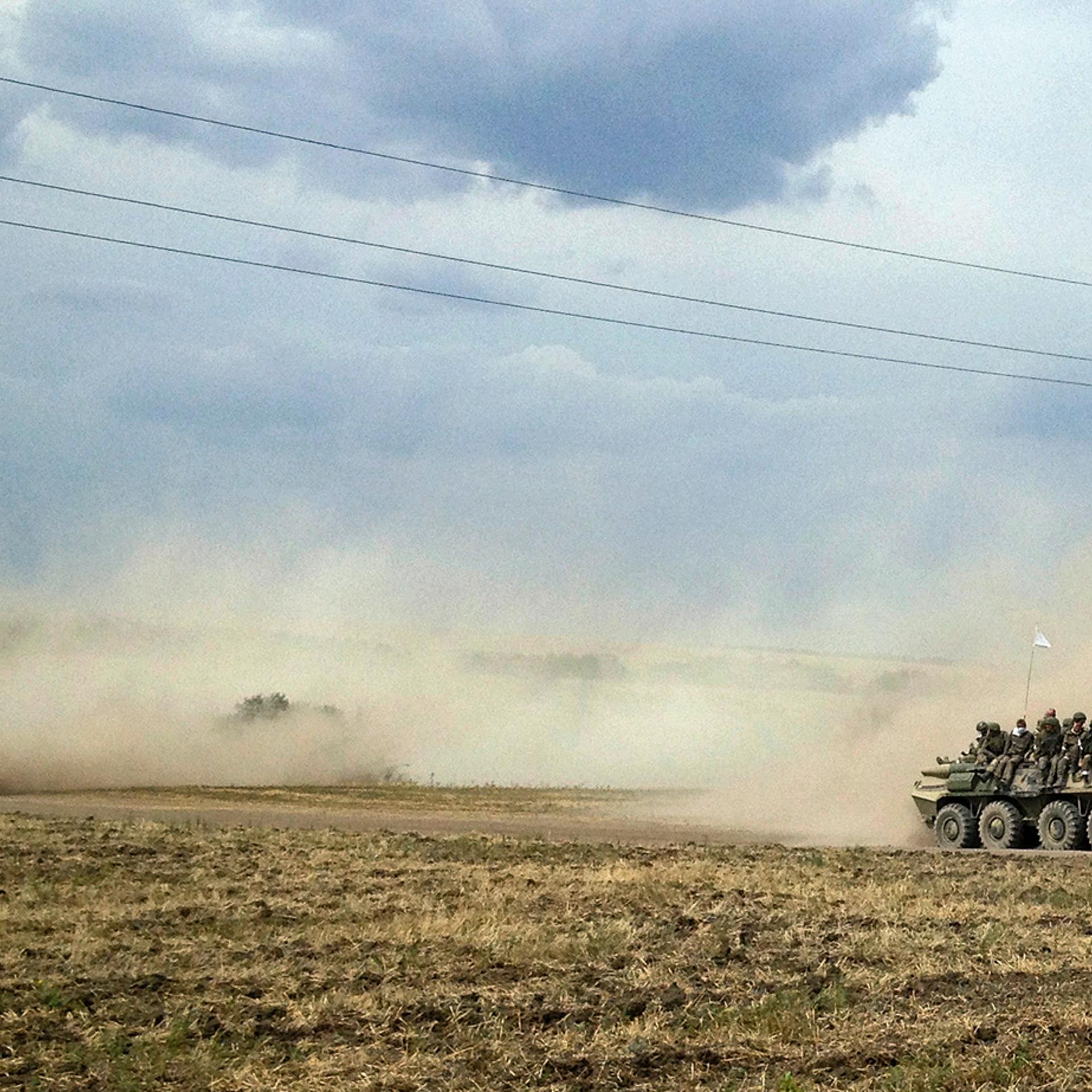 Servicemen sit atop an armoured vehicle as they travel through the steppe near the village of Krasnodarovka in Rostov region