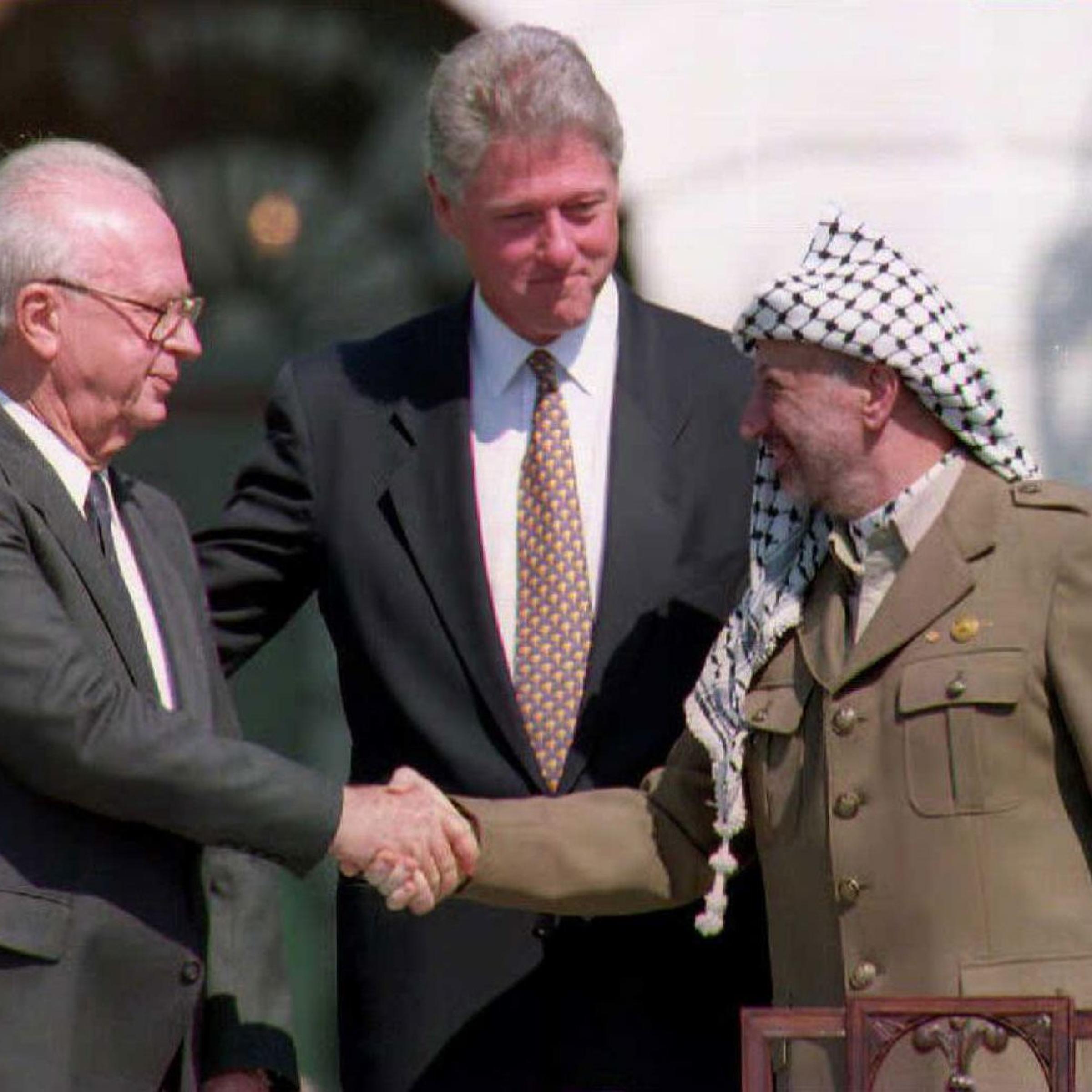 U.S. President Bill Clinton (C) stands between PLO leader Yasser Arafat (R) and Israeli Prime Minister Yitzahk Rabin (L) as they shake hands at the White House in Washington D.C. on Sept. 13, 1993.