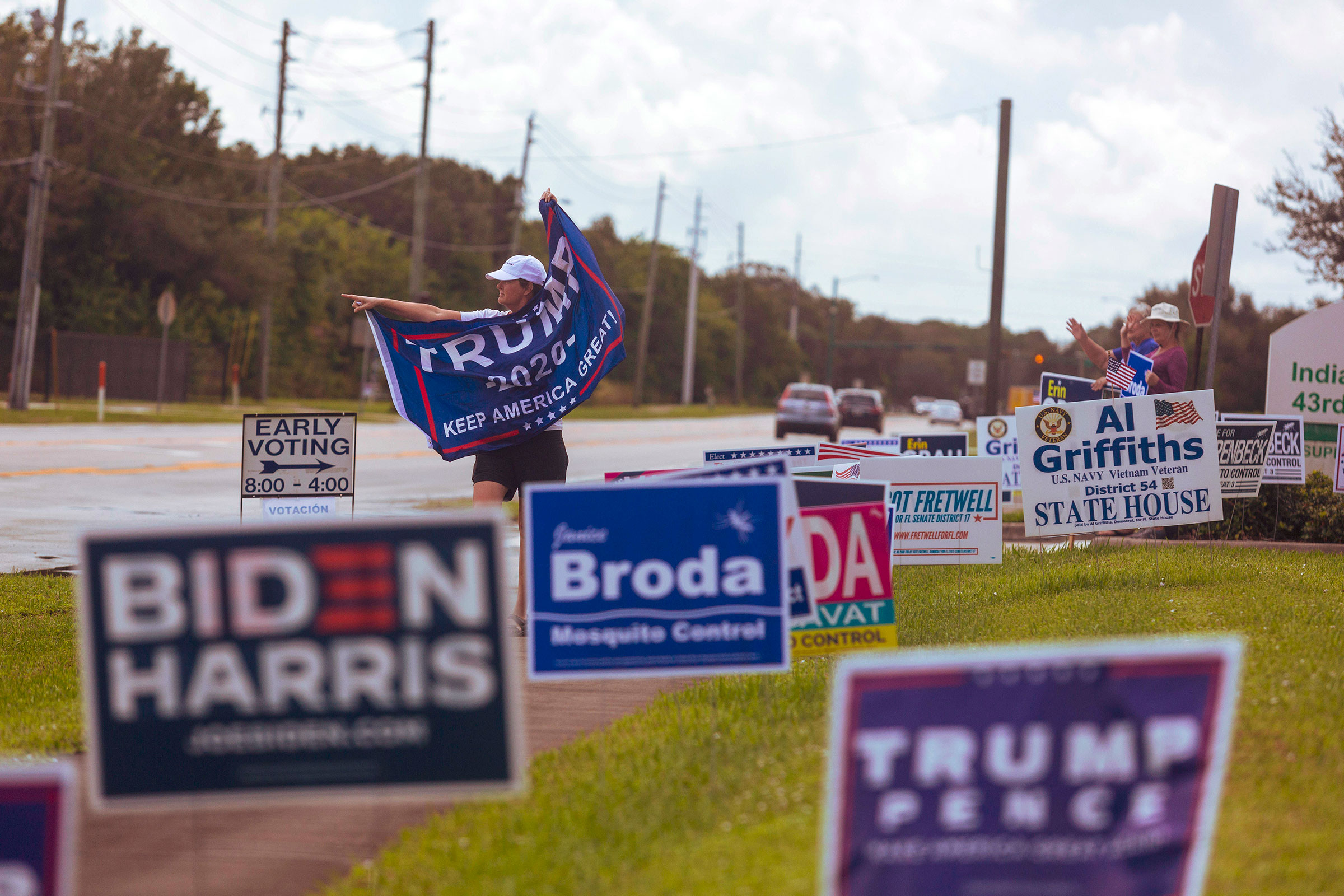 A person waves a Trump flag near a polling place in Vero Beach, Fla., Friday, Oct. 23, 2020. (Saul Martinez/The New York Times)