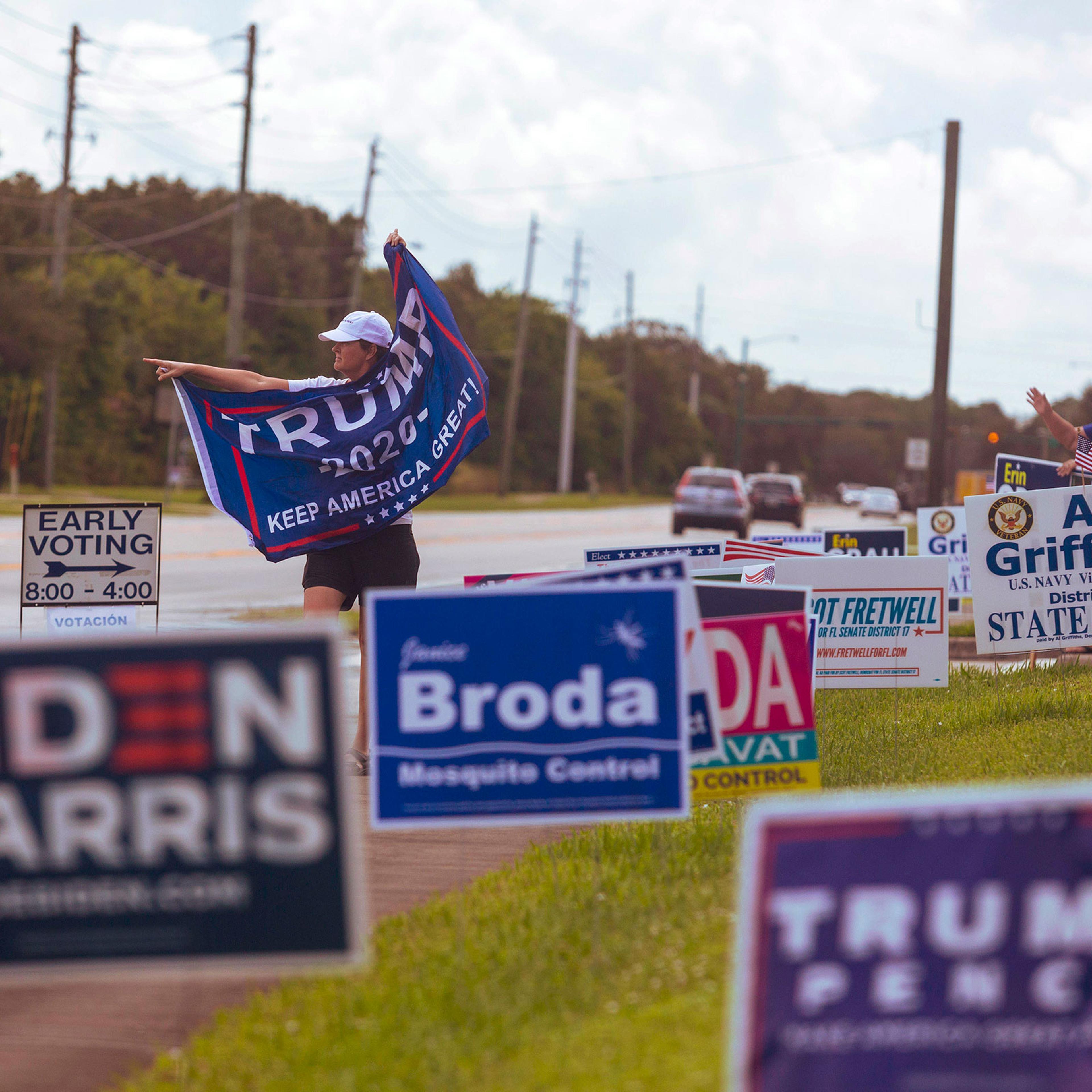 A person waves a Trump flag near a polling place in Vero Beach, Fla., Friday, Oct. 23, 2020. (Saul Martinez/The New York Times)