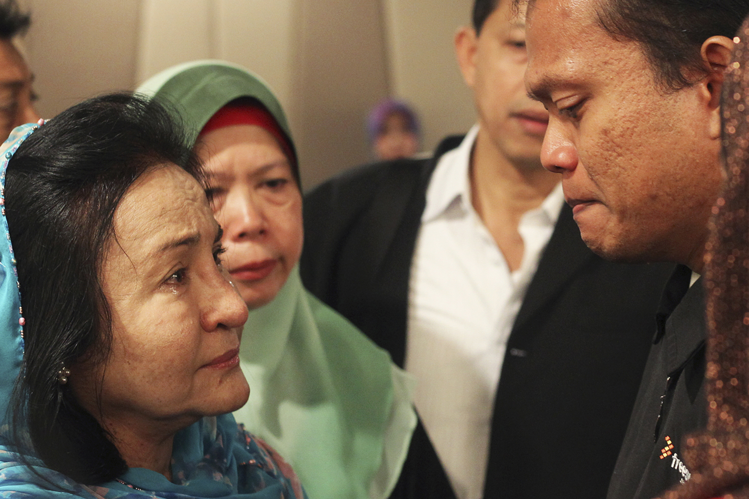 Rosmah Mansor, left, wife of Malaysian Prime Minister Najib Razak, cries with family members of passengers on the missing Malaysia Airlines flight MH370, at a hotel in Putrajaya March 9, 2014.