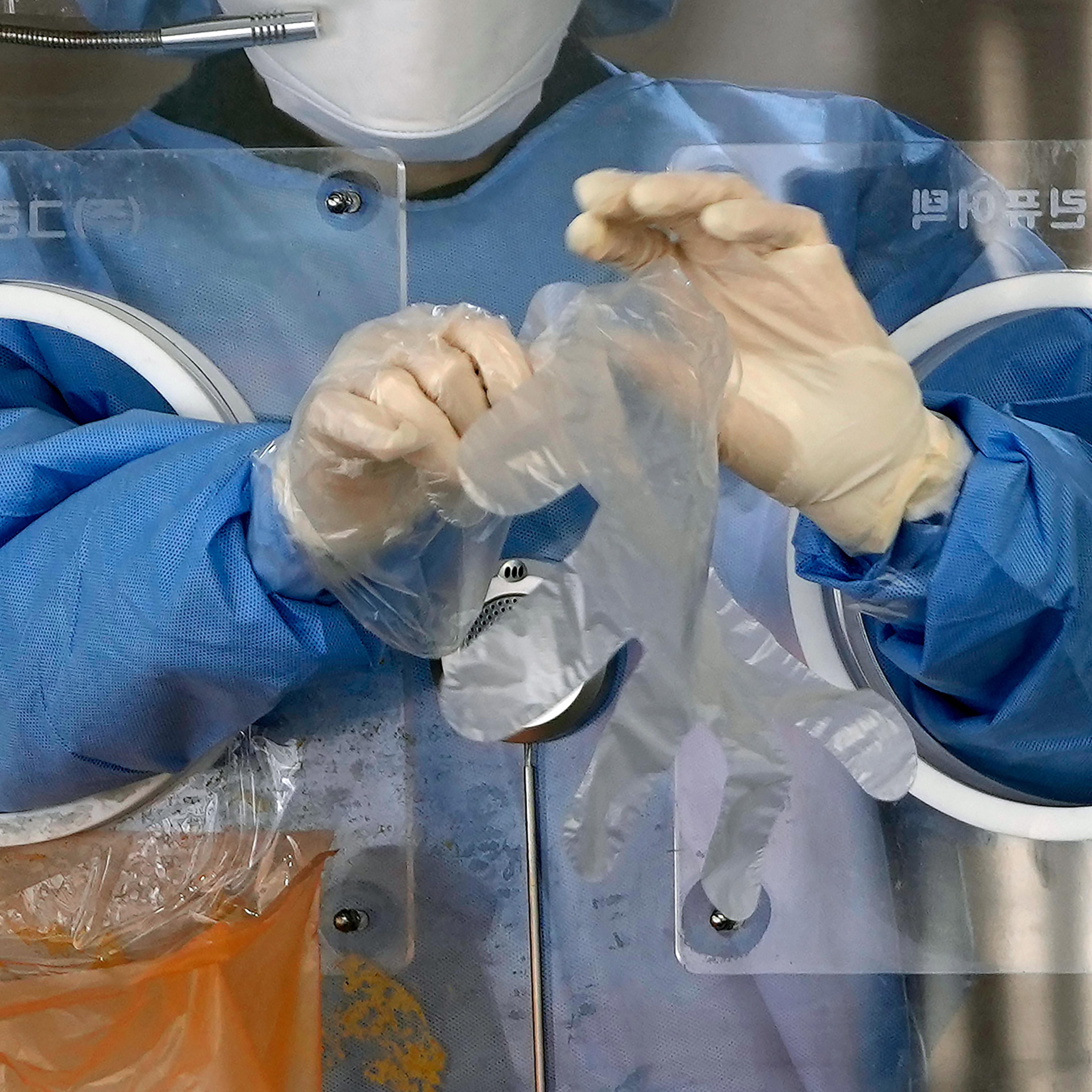 A medical worker wears plastic gloves at a temporary screening clinic