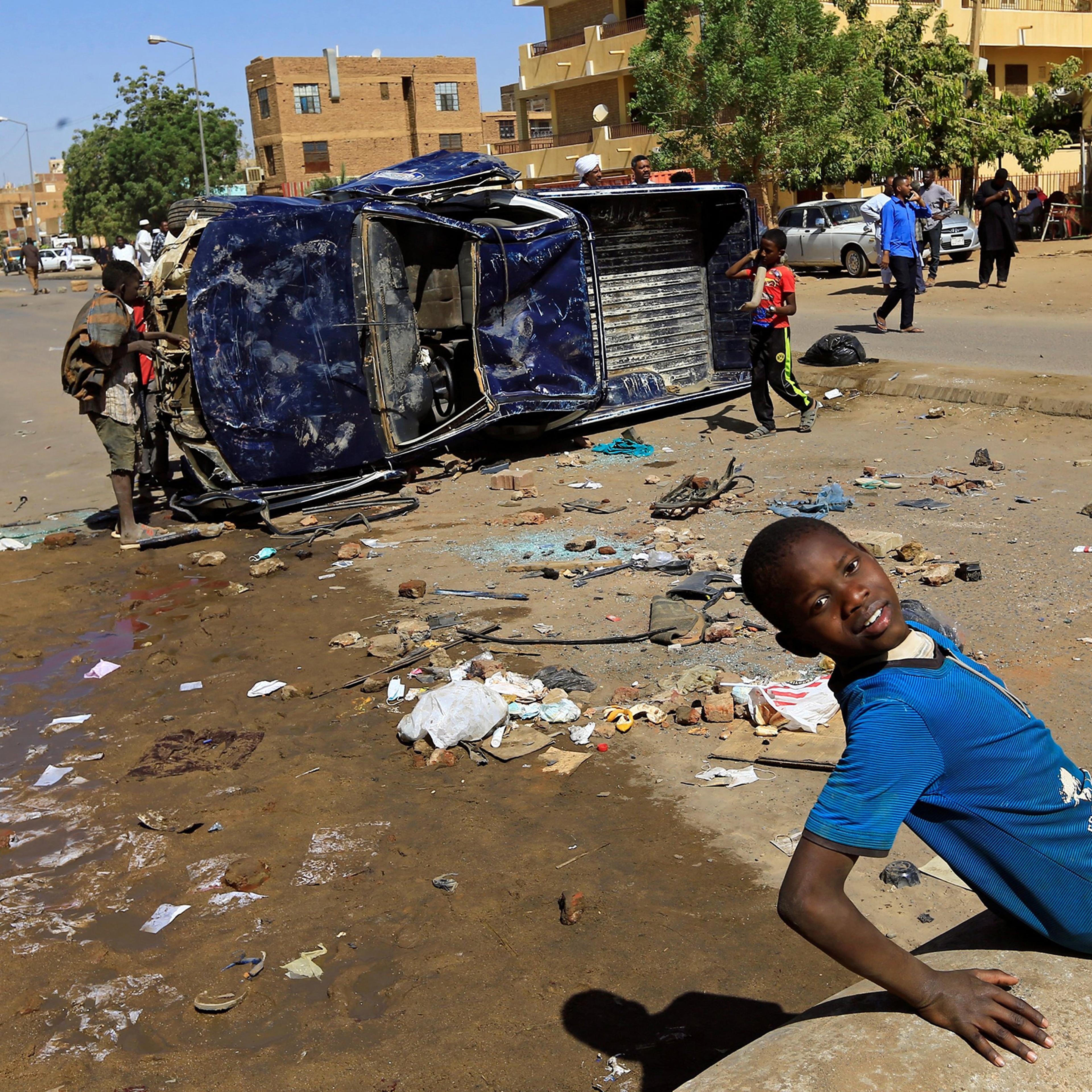 Children play near a police car flipped over and damaged by mourners near the home of a demonstrator who died of a gunshot wound sustained during anti-government protests in Khartoum, Sudan January 18, 2019.