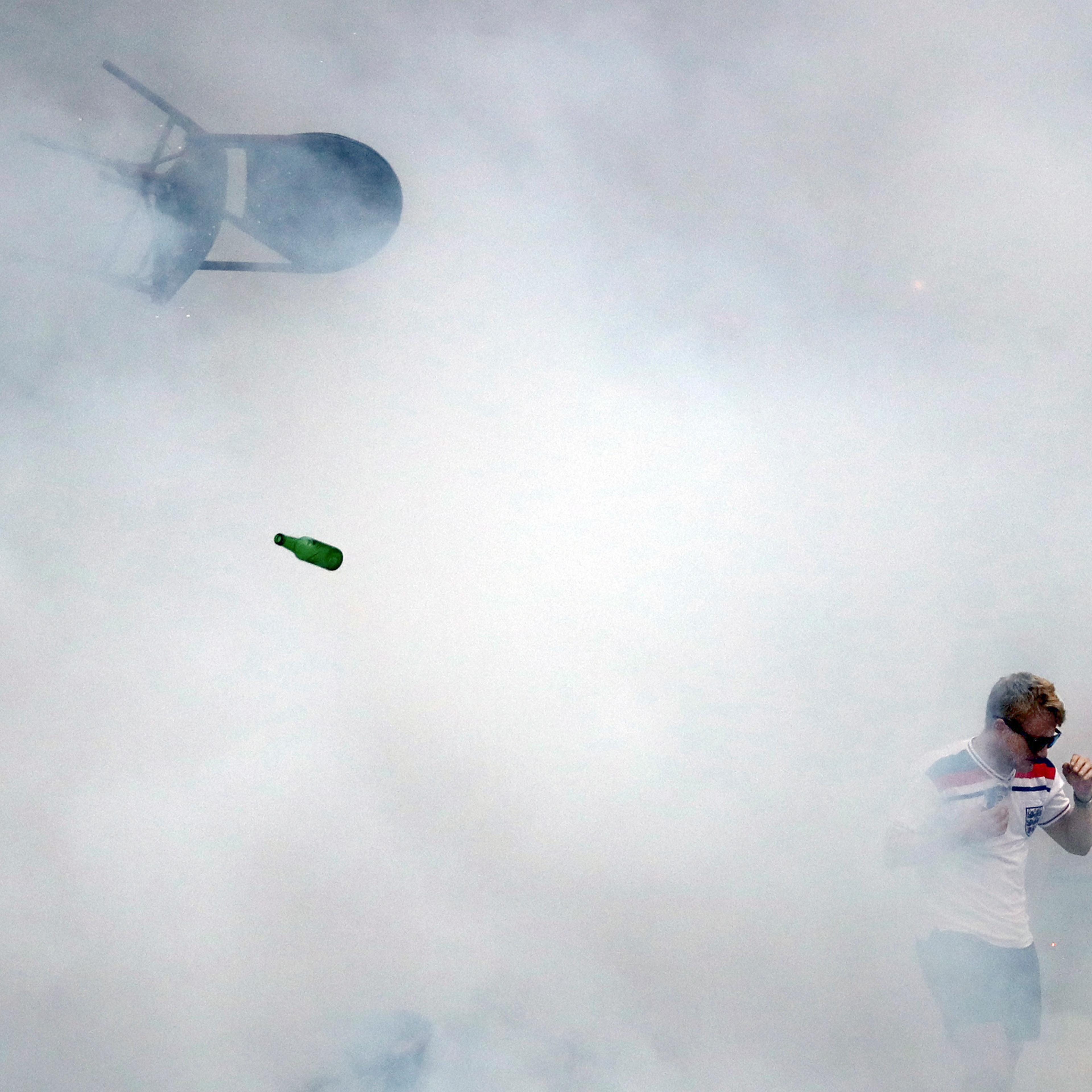 A bottle and chair are thrown as an England fan walks through tear gas as England fans clash with police in Marseille, France, on June 10, 2016.
