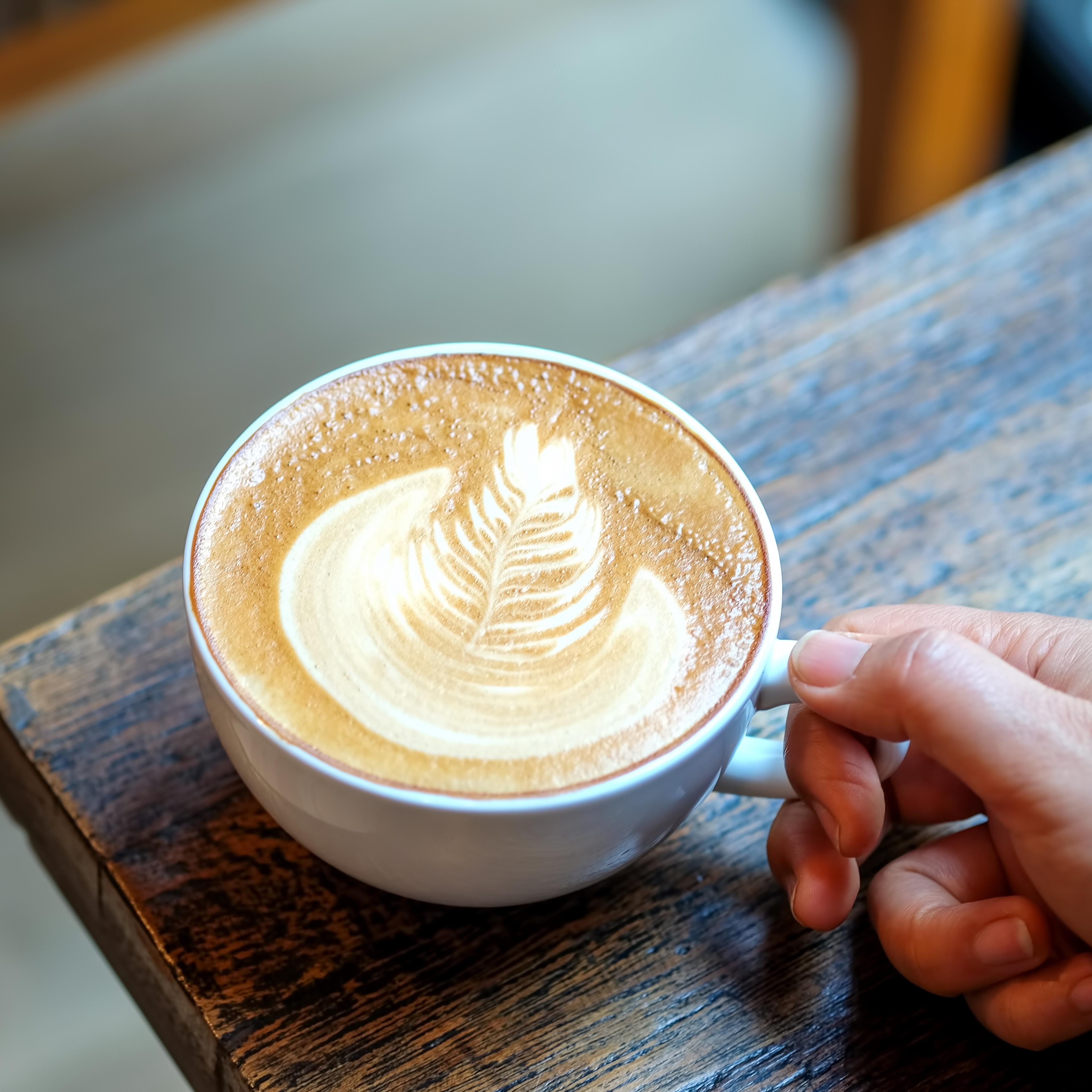 Hand on latte leaves tree coffee cup.