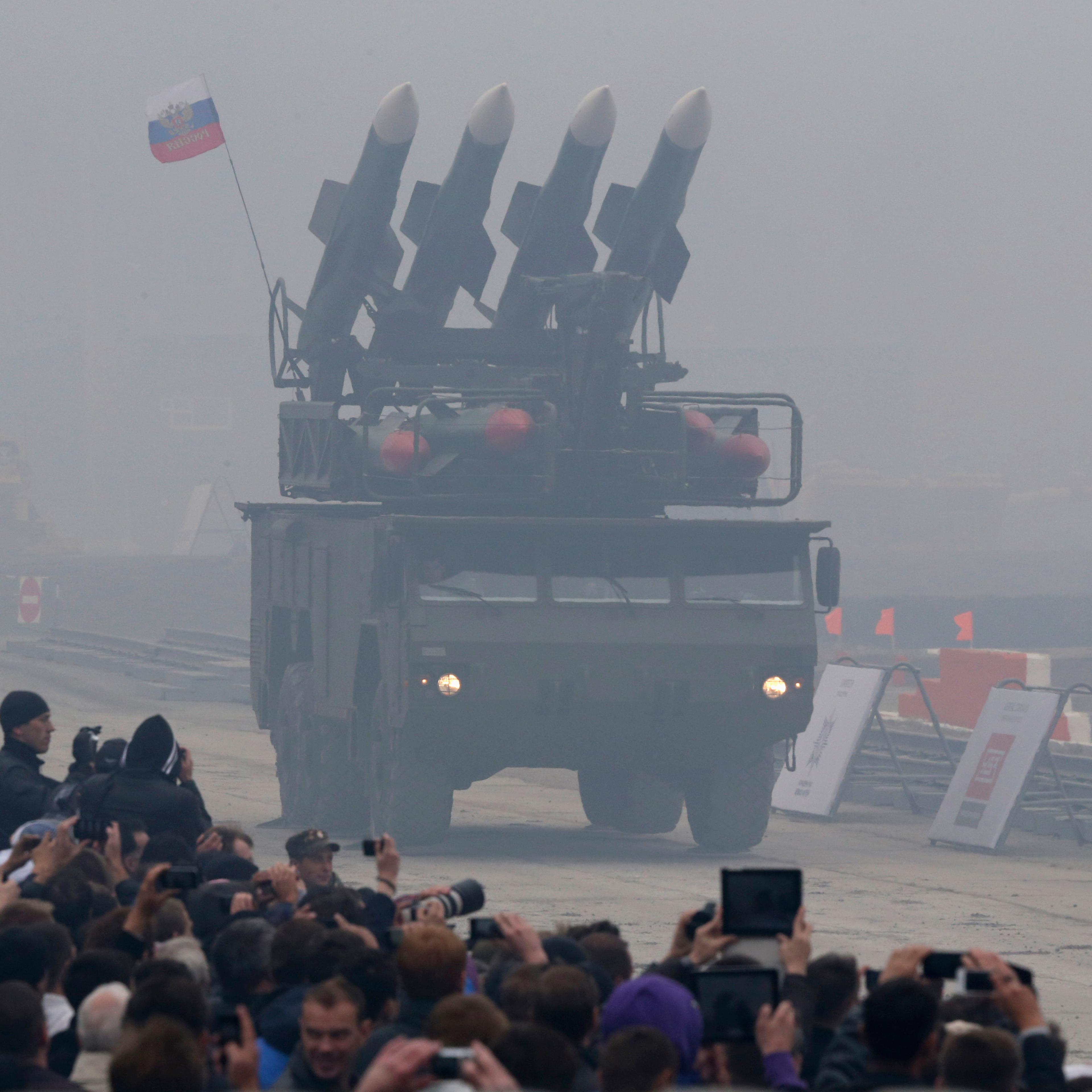 Spectators watch a Russian "Buk" missile system being driven during the "Russia Arms Expo 2013" 9th international exhibition of arms, military equipment and ammunition, in the Urals city of Nizhny Tagil