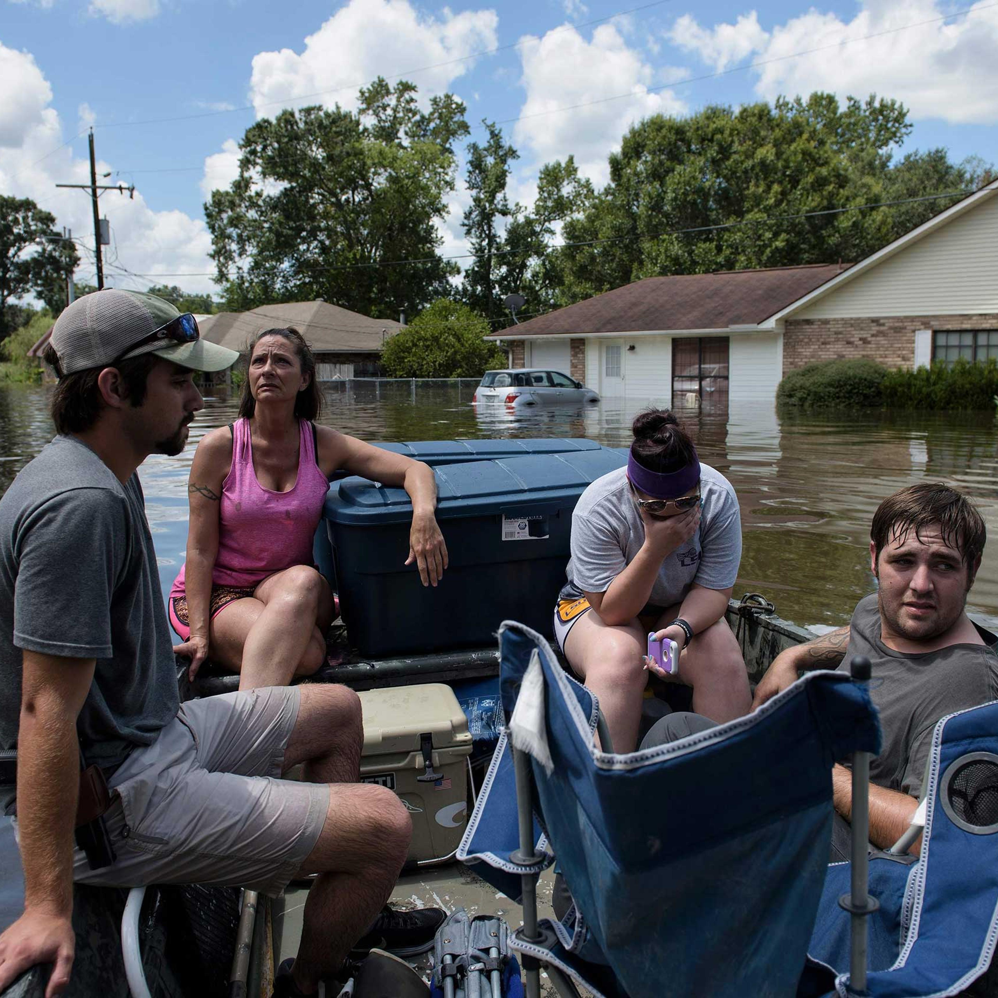 John Booth, left, sits with Angela Latiolais's family while helping them save belongings after flooding in Gonzales, La., on Aug. 16, 2016.