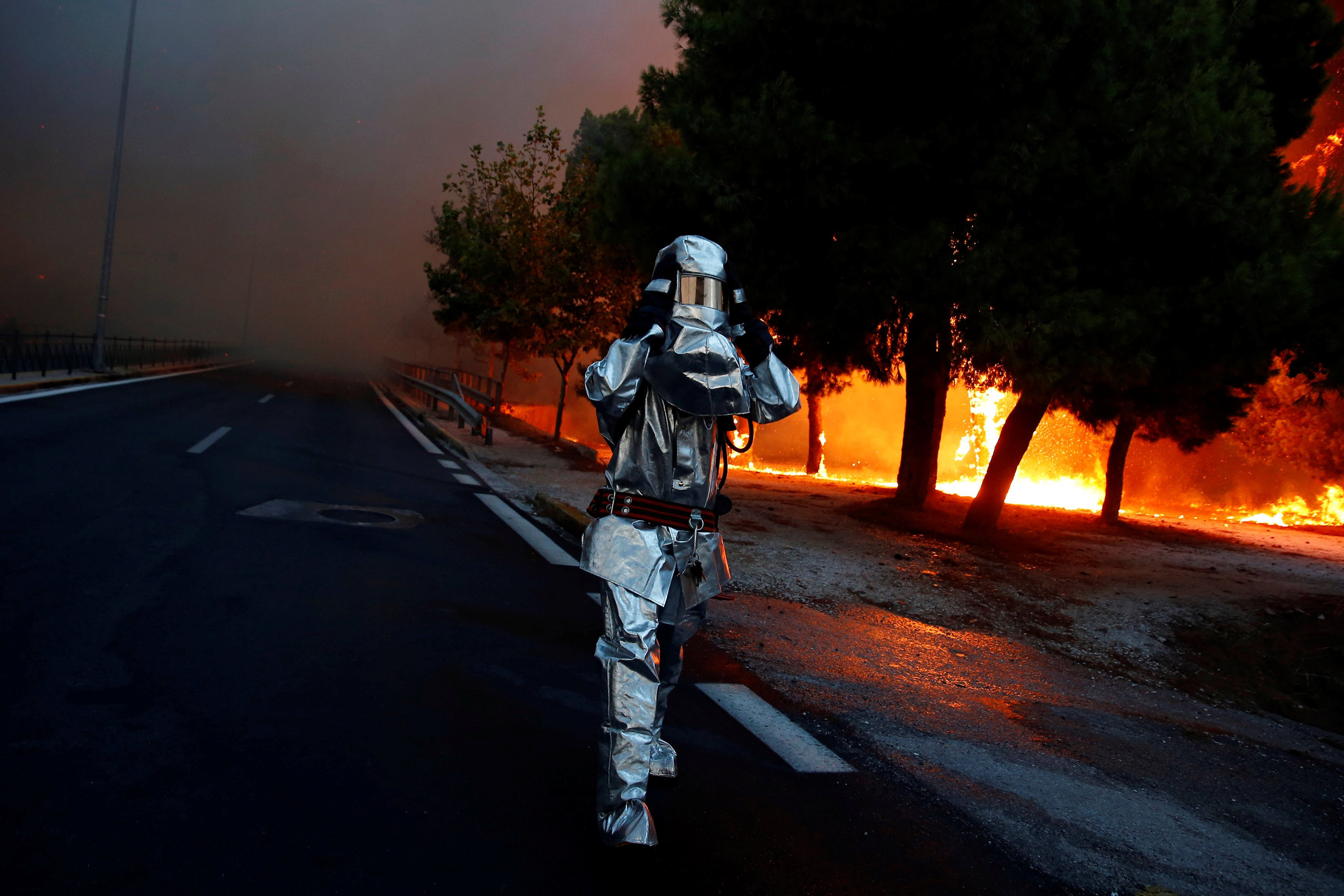 A firefighter wears a flame resistant uniform as wildfire burns in the town of Rafina, near Athens