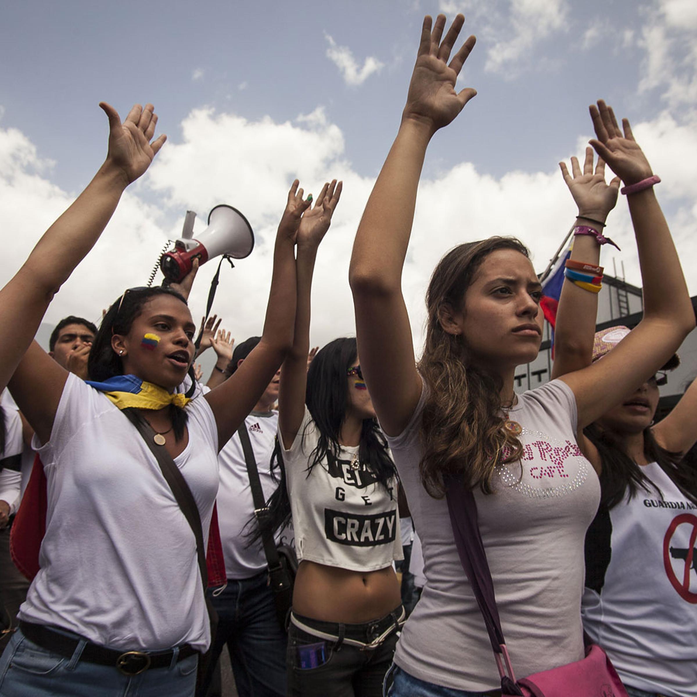 Protesters raise their hands in a sign of peace after the Bolivarian National Guard cut the march in two parts, not allowing part of the march to continue, Caracas, March 4, 2013.