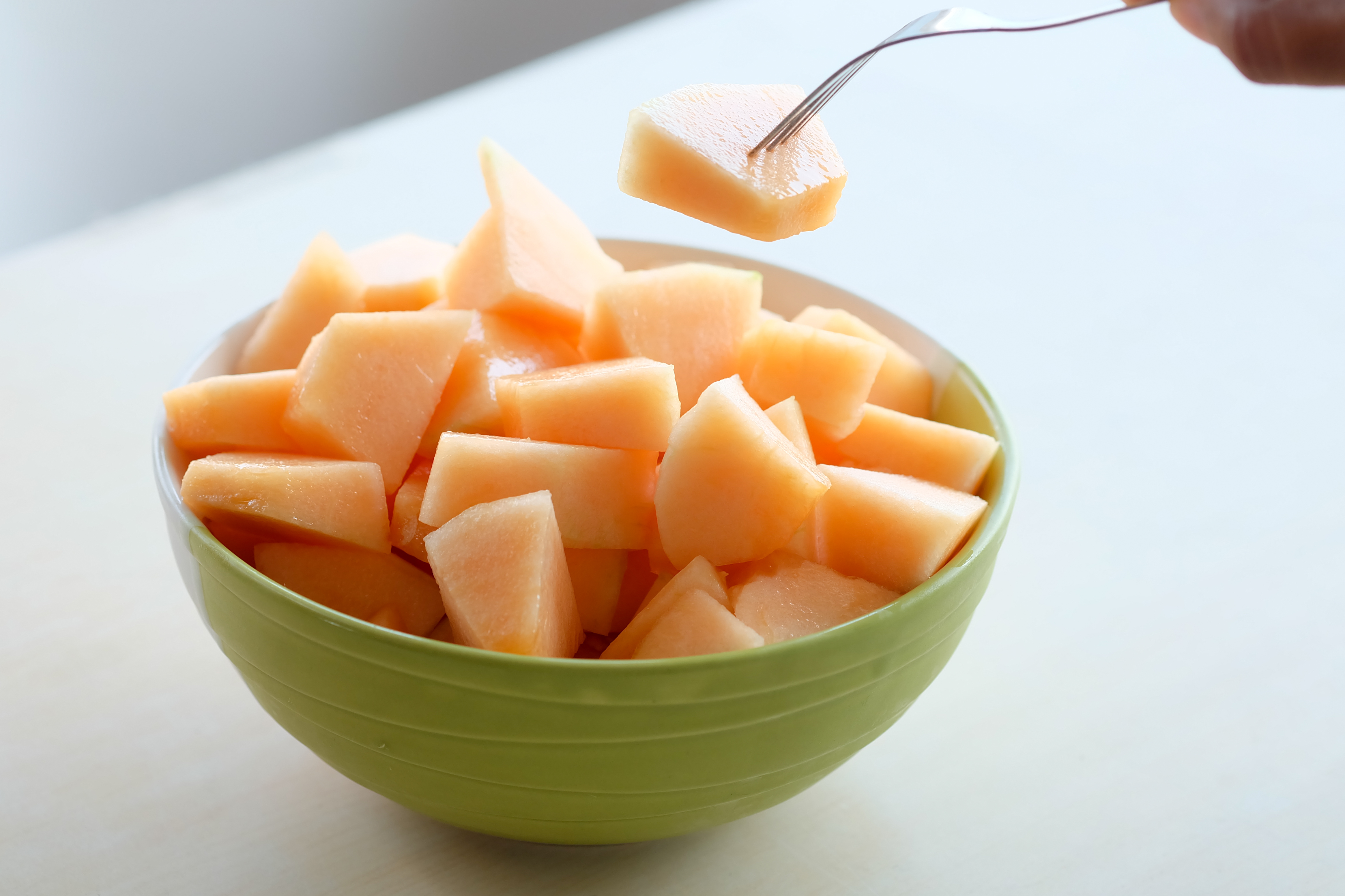 hands of the people are using the fork to melt the orange Melon