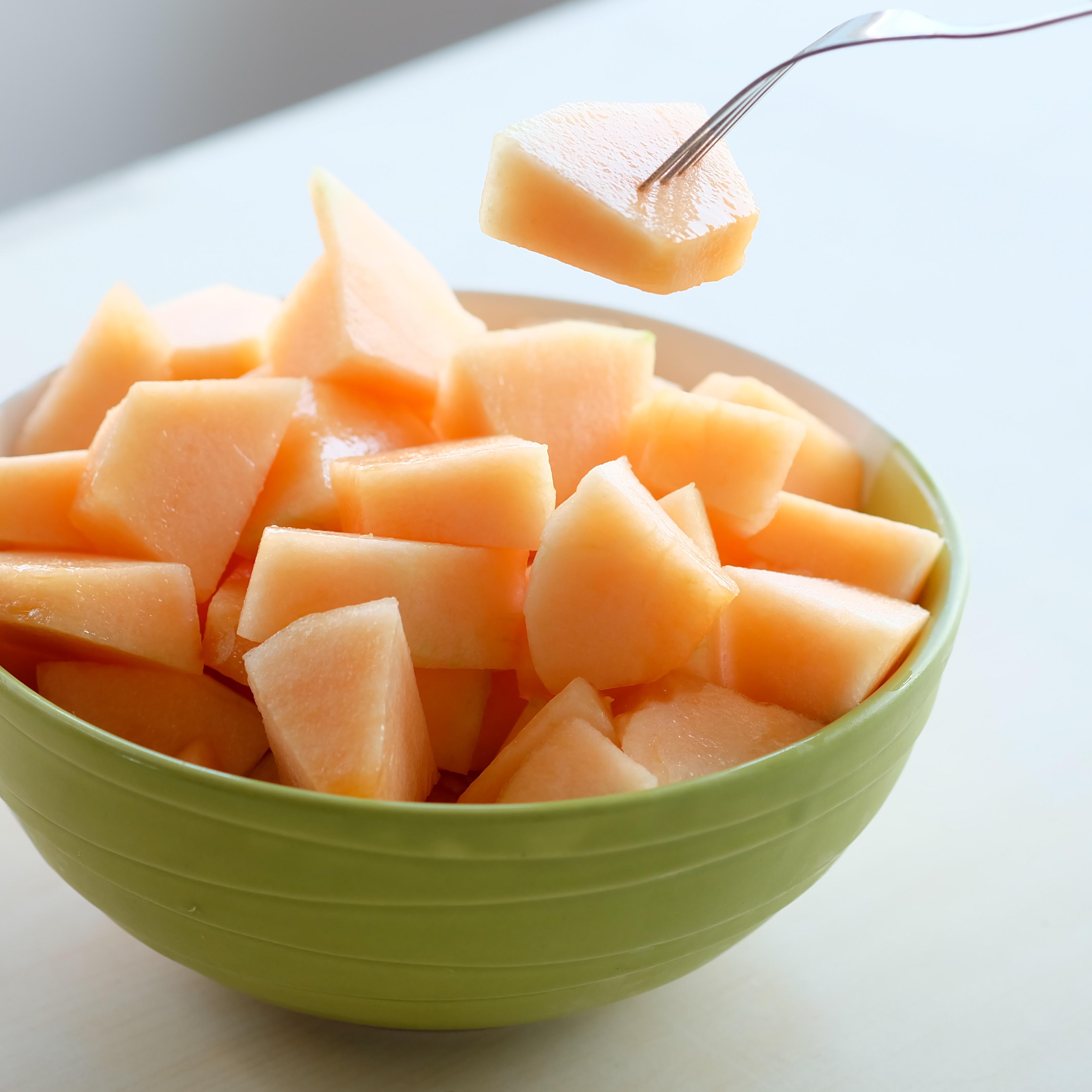 hands of the people are using the fork to melt the orange Melon