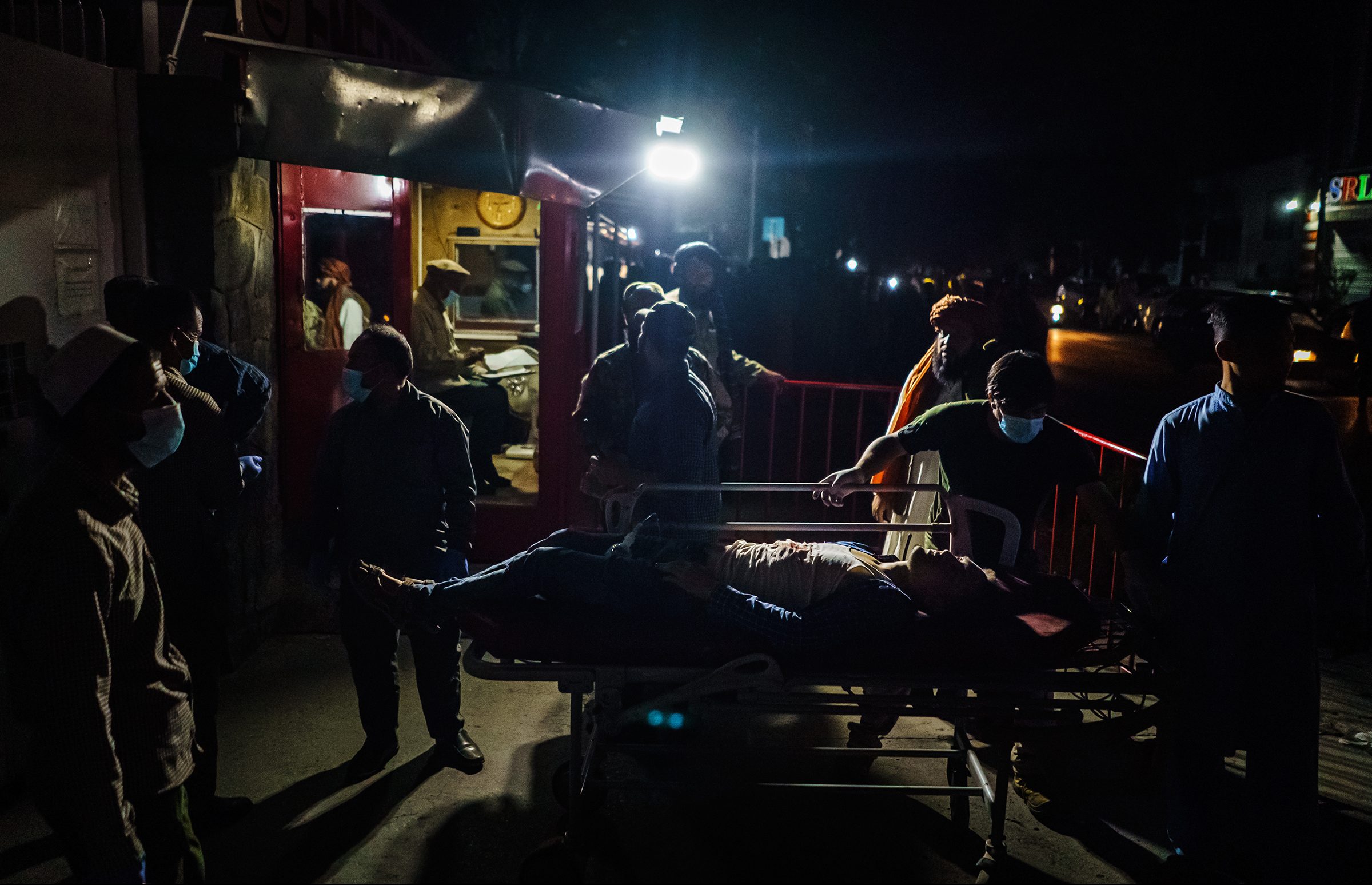 Hospital staff help bring in a wounded patient brought by an ambulance at an emergency hospital in Kabul, Aug. 26. Twin bombings struck near the entrance to Kabul's airport on Thursday.
