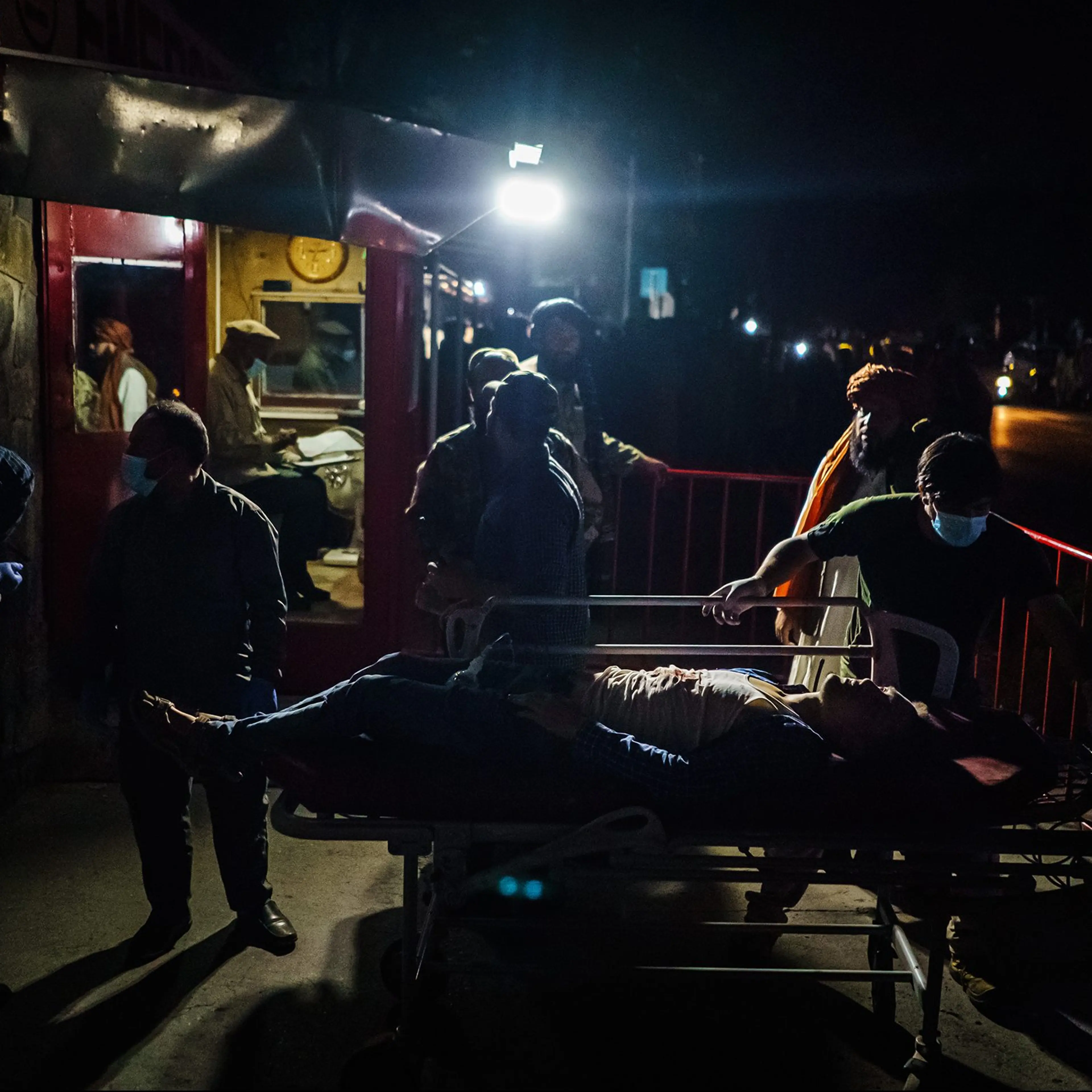 Hospital staff help bring in a wounded patient brought by an ambulance at an emergency hospital in Kabul, Aug. 26. Twin bombings struck near the entrance to Kabul's airport on Thursday.