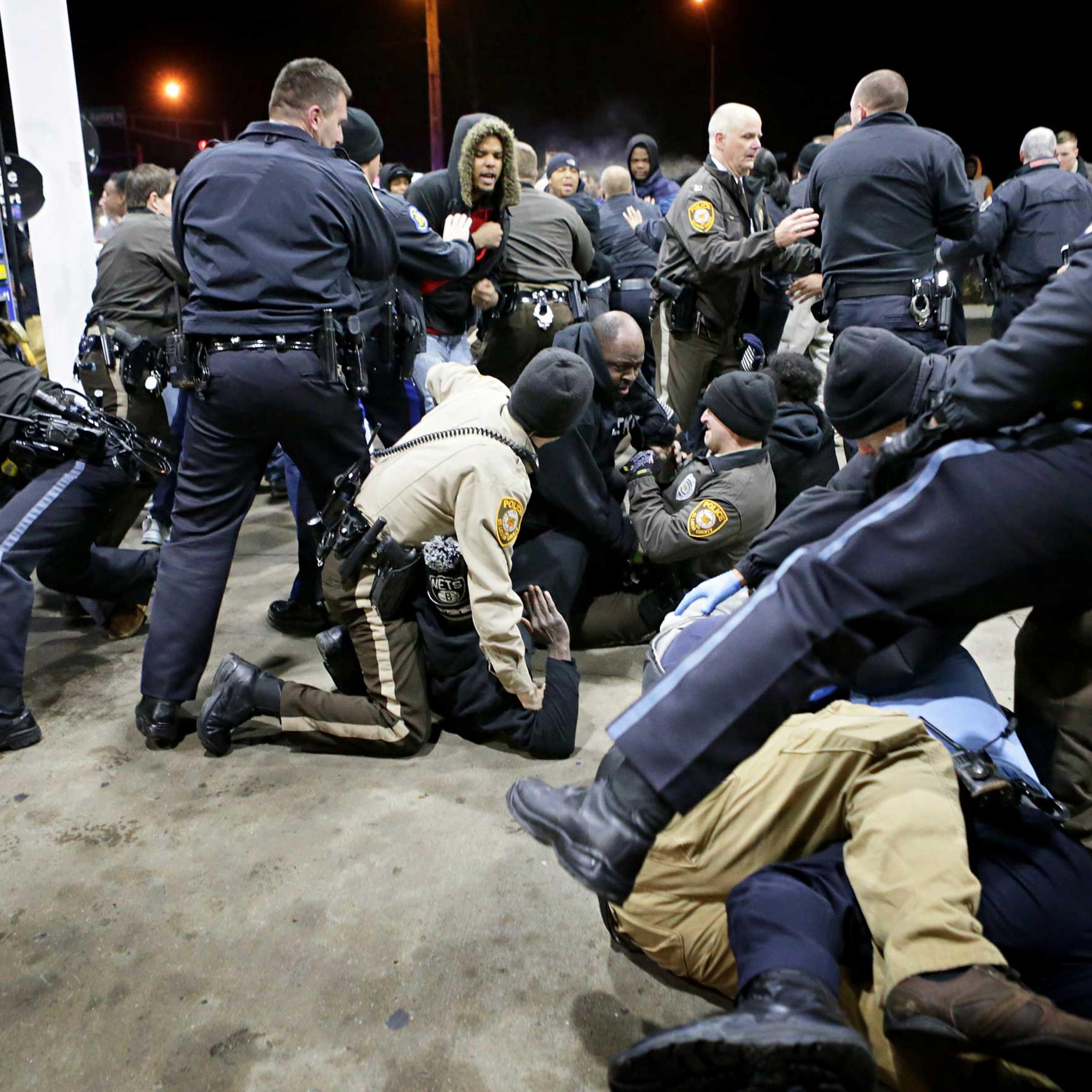 Police try to control a crowd on Dec. 24, 2014, on the lot of a gas station following a shooting Tuesday in Berkeley, Mo.