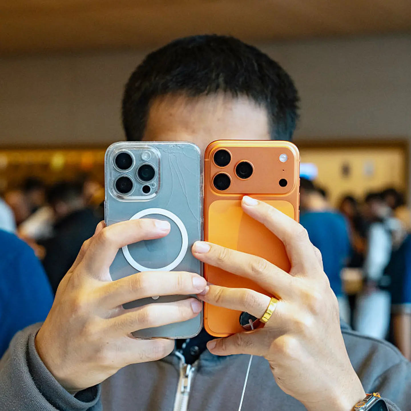 A person holds two smartphones up to their face.
