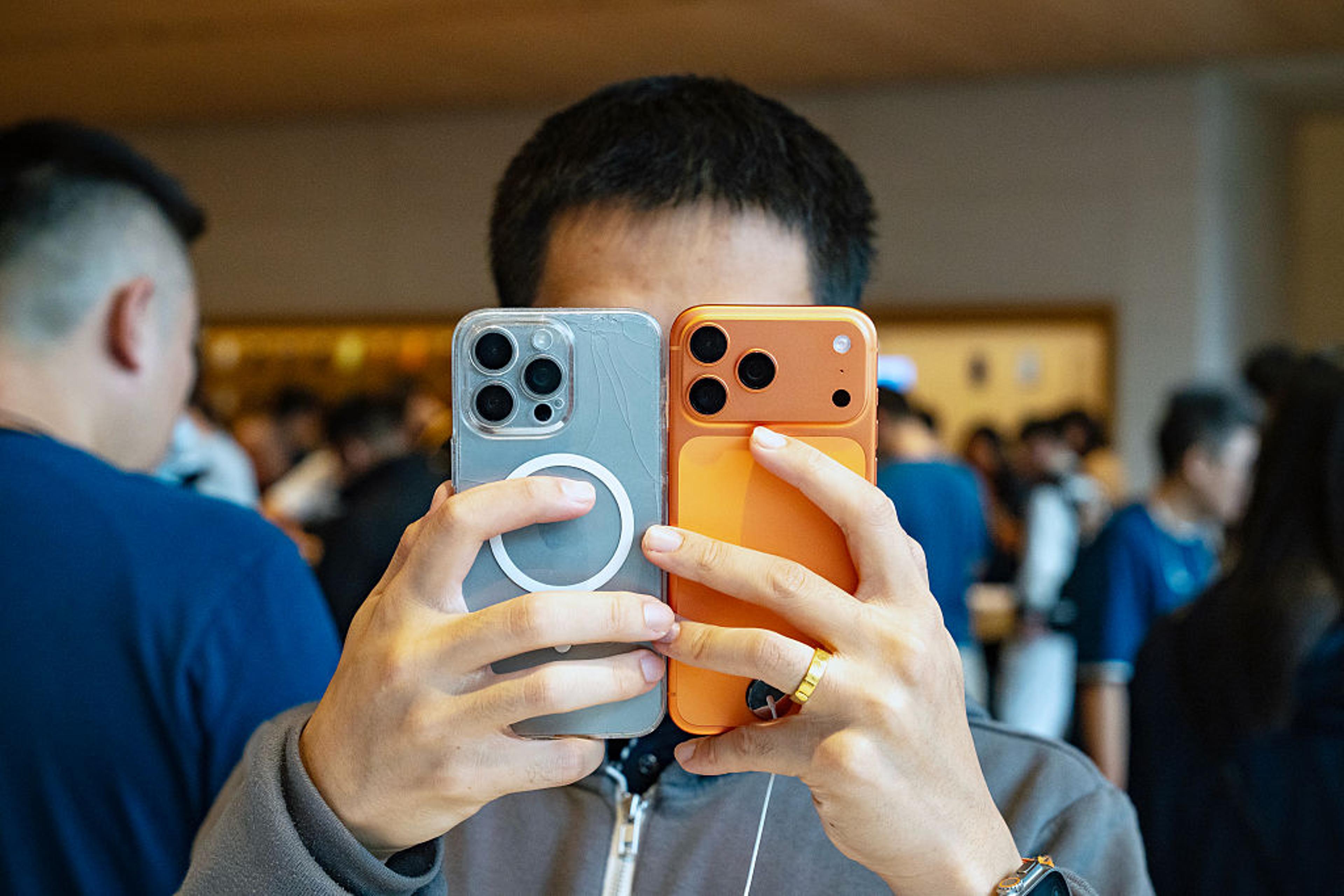 A person holds two smartphones up to their face.