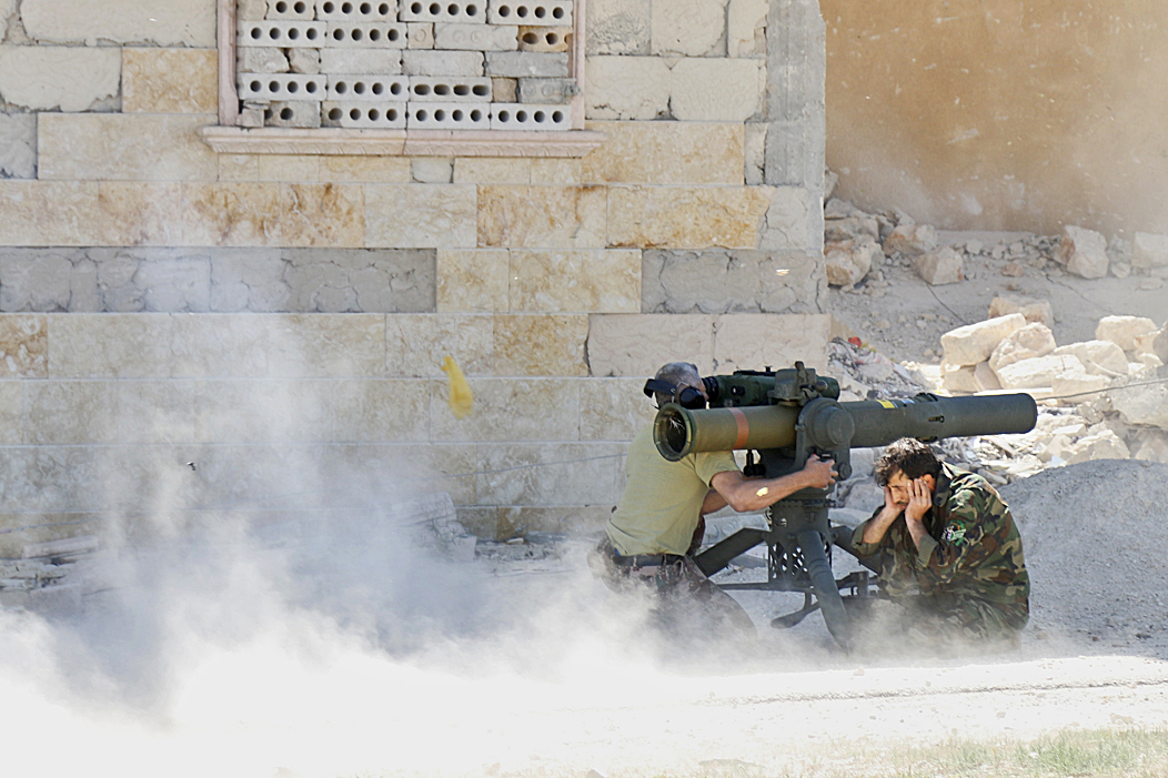 Rebel fighters fire an anti-tank missile weapon towards forces loyal to Syria's President al-Assad stationed in Maaret al-Naaman village