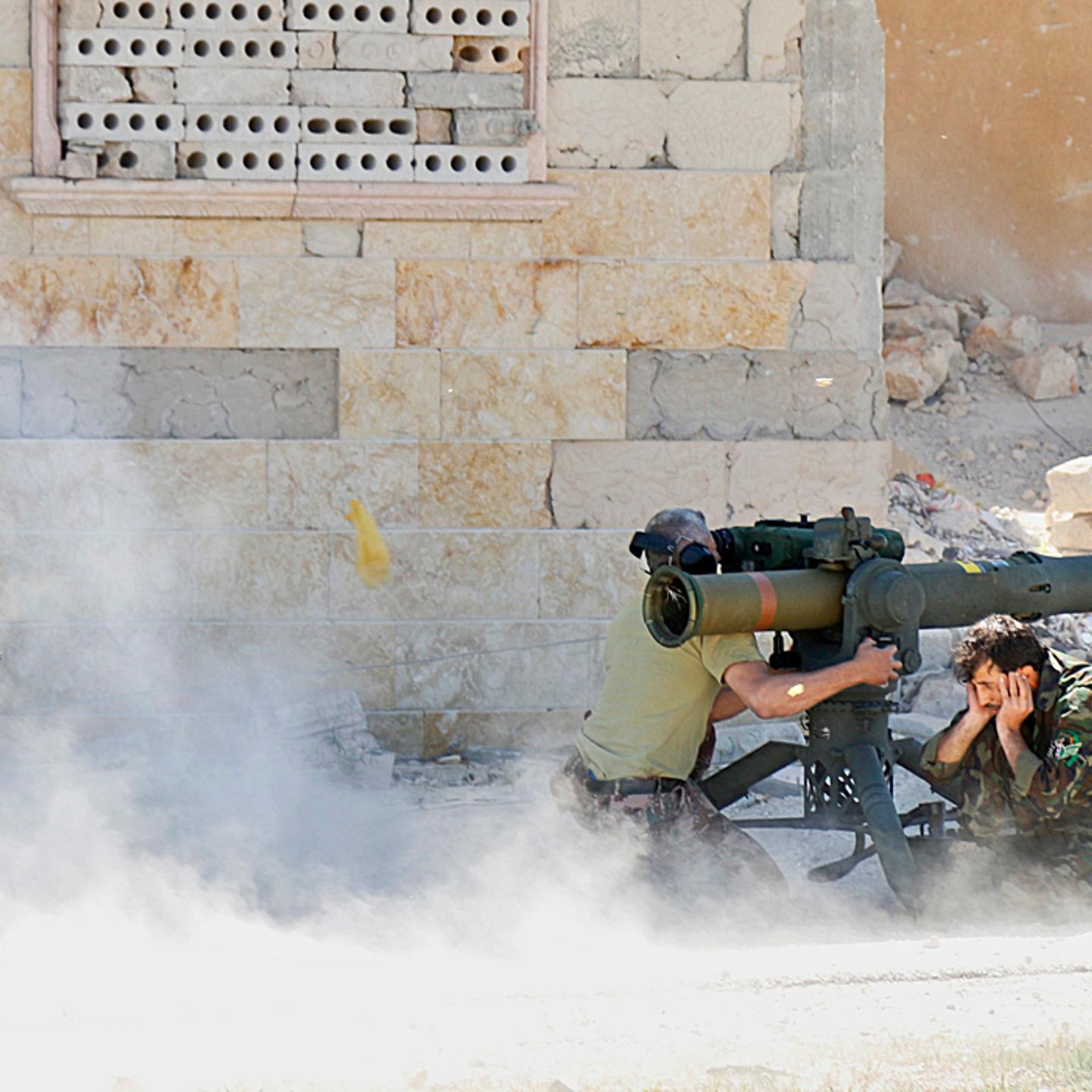 Rebel fighters fire an anti-tank missile weapon towards forces loyal to Syria's President al-Assad stationed in Maaret al-Naaman village