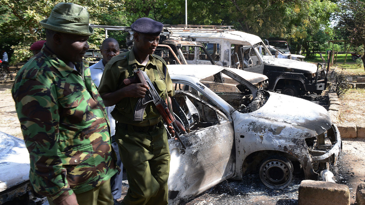 Kenya police observe the remains of burnt-out cars at a police station in Mpeketoni, Lamu county on June 16, 2014 after some 50 heavily-armed gunmen attacked the town near the coastal island and popular tourist resort of lamu the night before. At least 49 people were killed when suspected Shebab militants from Somalia stormed into a Kenyan coastal town and launched a major assault on a police station, hotels and government offices, officials said June 16. 